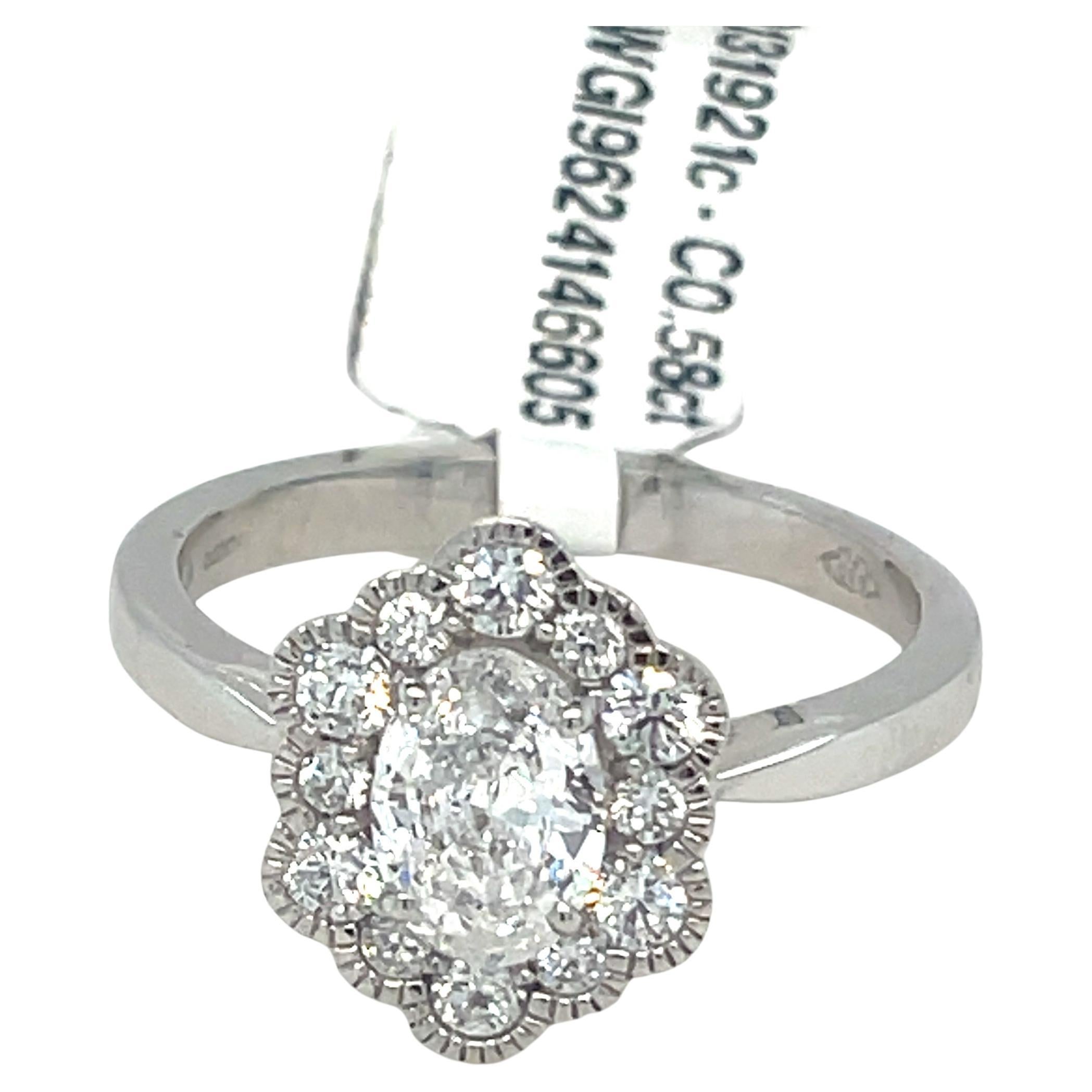 Questo splendido anello a grappolo in platino è un gioiello senza tempo. Il suo design elegante presenta una pietra centrale scintillante circondata da un'aureola di diamanti più piccoli.

Pietra centrale: diamante di taglio ovale da 0,58 carati