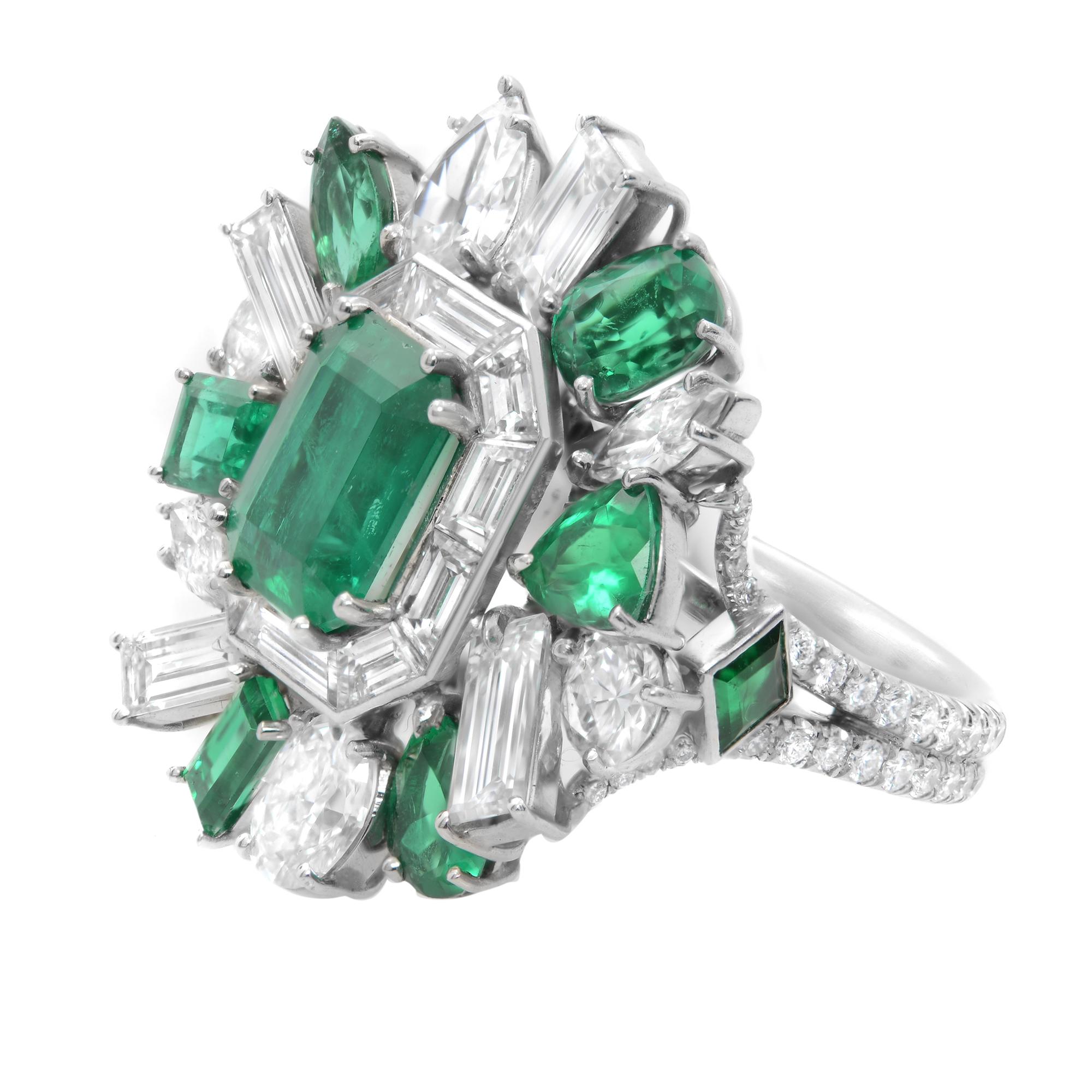 This spectacular platinum cocktail ring presents an excellent quality Green Emerald of 2.92 carats in the center. The rest of the ring is set with deep colored, different shapes emeralds and contrasted by diamonds. An entourage of further smaller