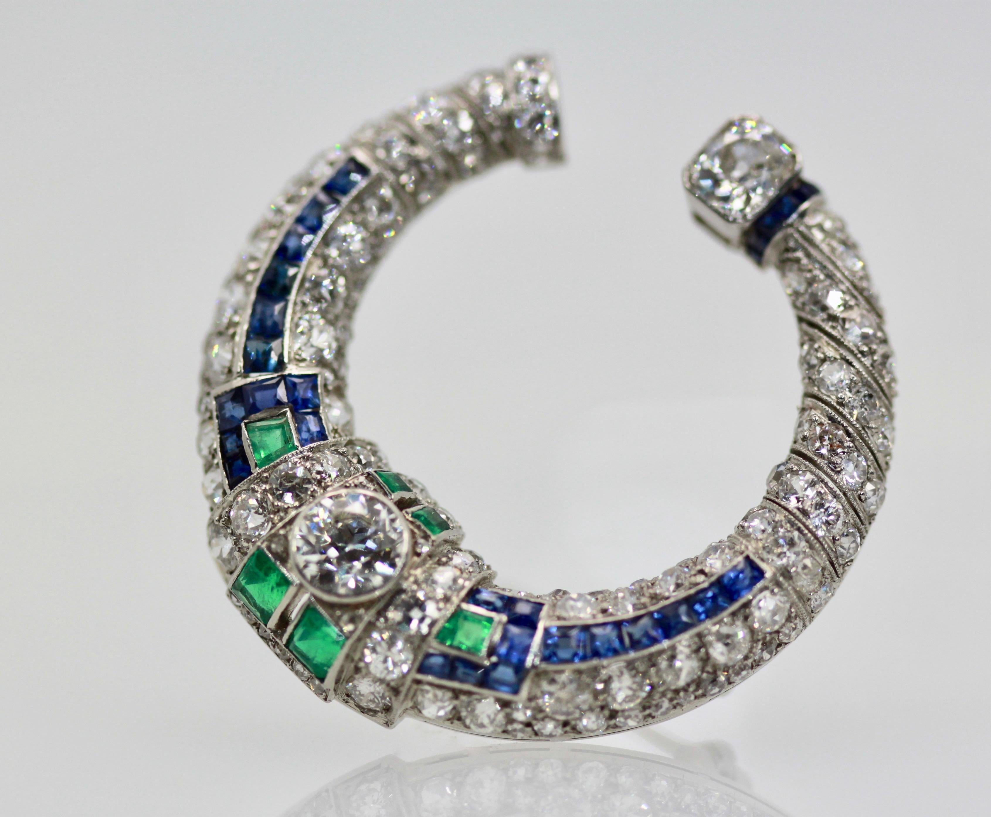 This Deco Platinum Sapphire and Emerald Brooch is shaped as a crescent or 