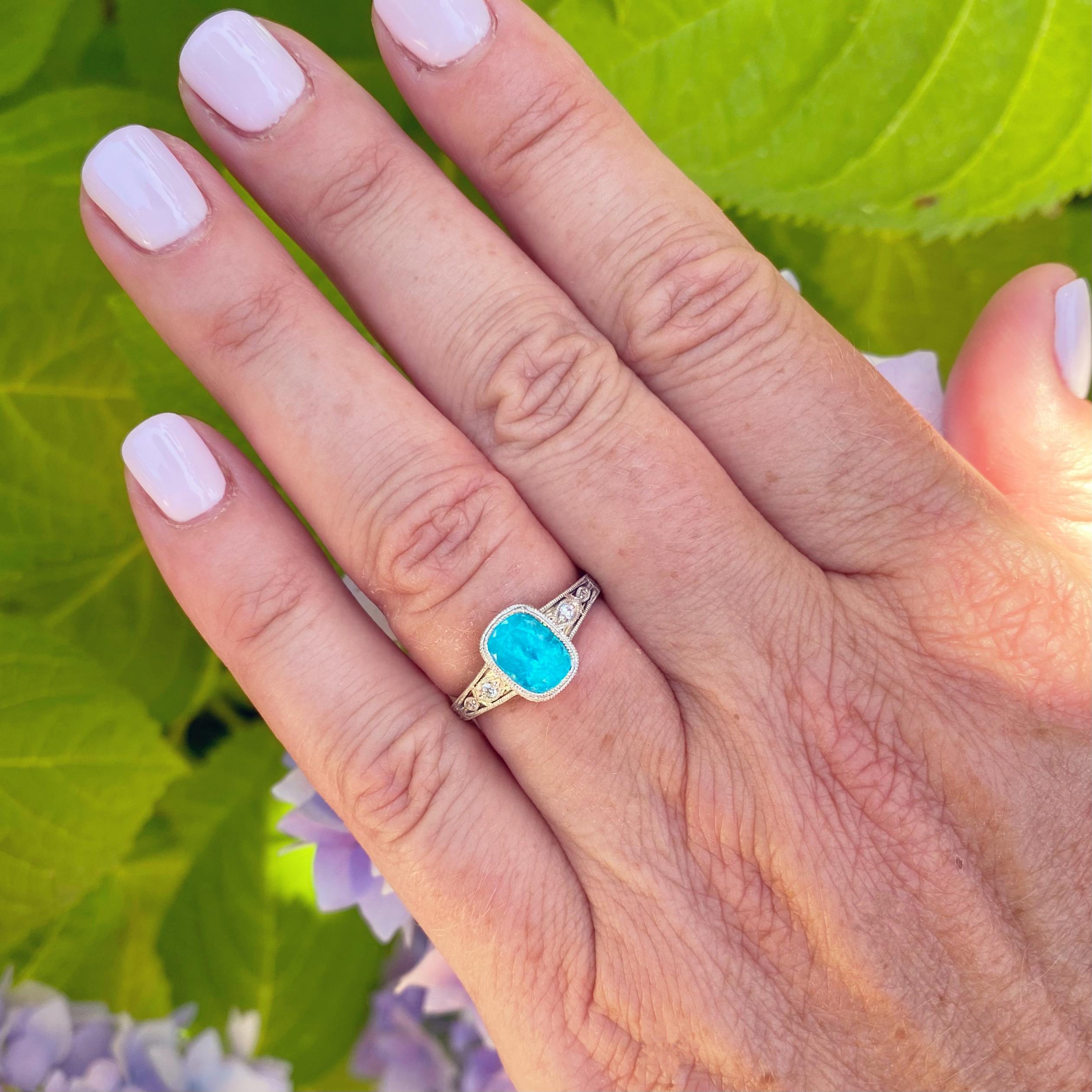 A true one of a kind! This electric green-blue Cushion Cut Paraiba Tourmaline is bezel set in an absolutely gorgeous Art Deco inspired platinum ring. The 1.63 carat Paraiba is accompanied by a GIA Tourmaline gemstone report. The platinum ring is