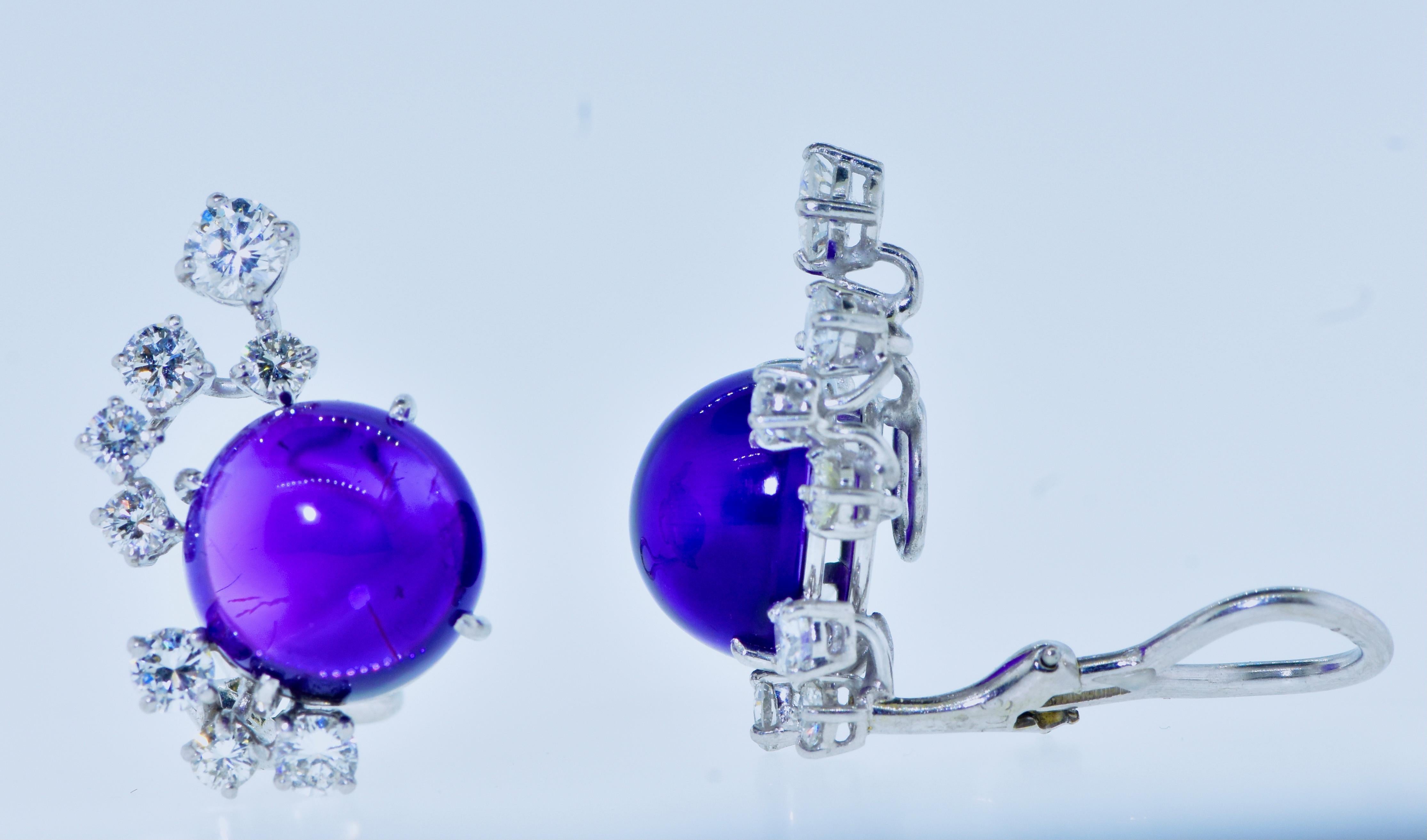 Amethyst, diamond and platinum earrings. The two amethysts weigh an estimated 7.6 cts. The stones are high cabochon cut, a deep velvety purple color with a hint of red undertones. 16 round brilliant cut white diamonds accent the amethysts. The
