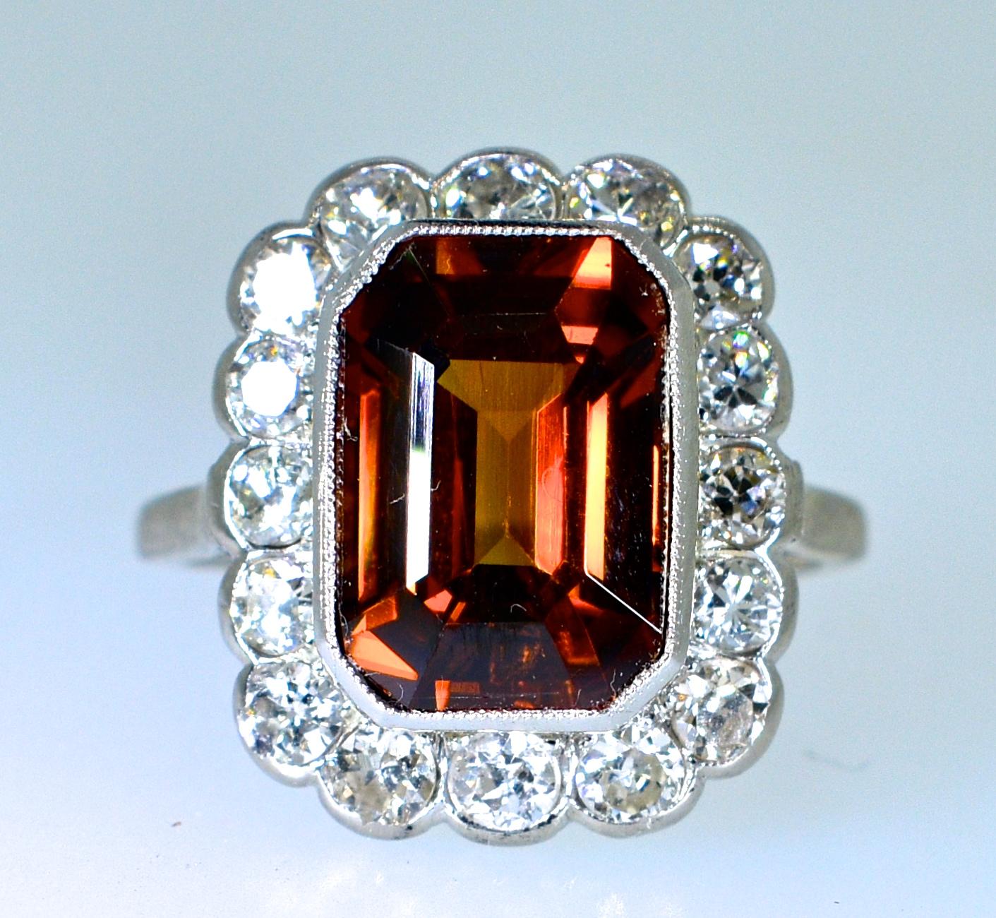 The center stone is a fine natural Zircon.  The tawny color is very unusual.  It's chestnut like color has flashes of red which one rarely sees.  This stone weighs approximately 10 cts. and is surrounded by fine white old cut diamonds.  The diamonds