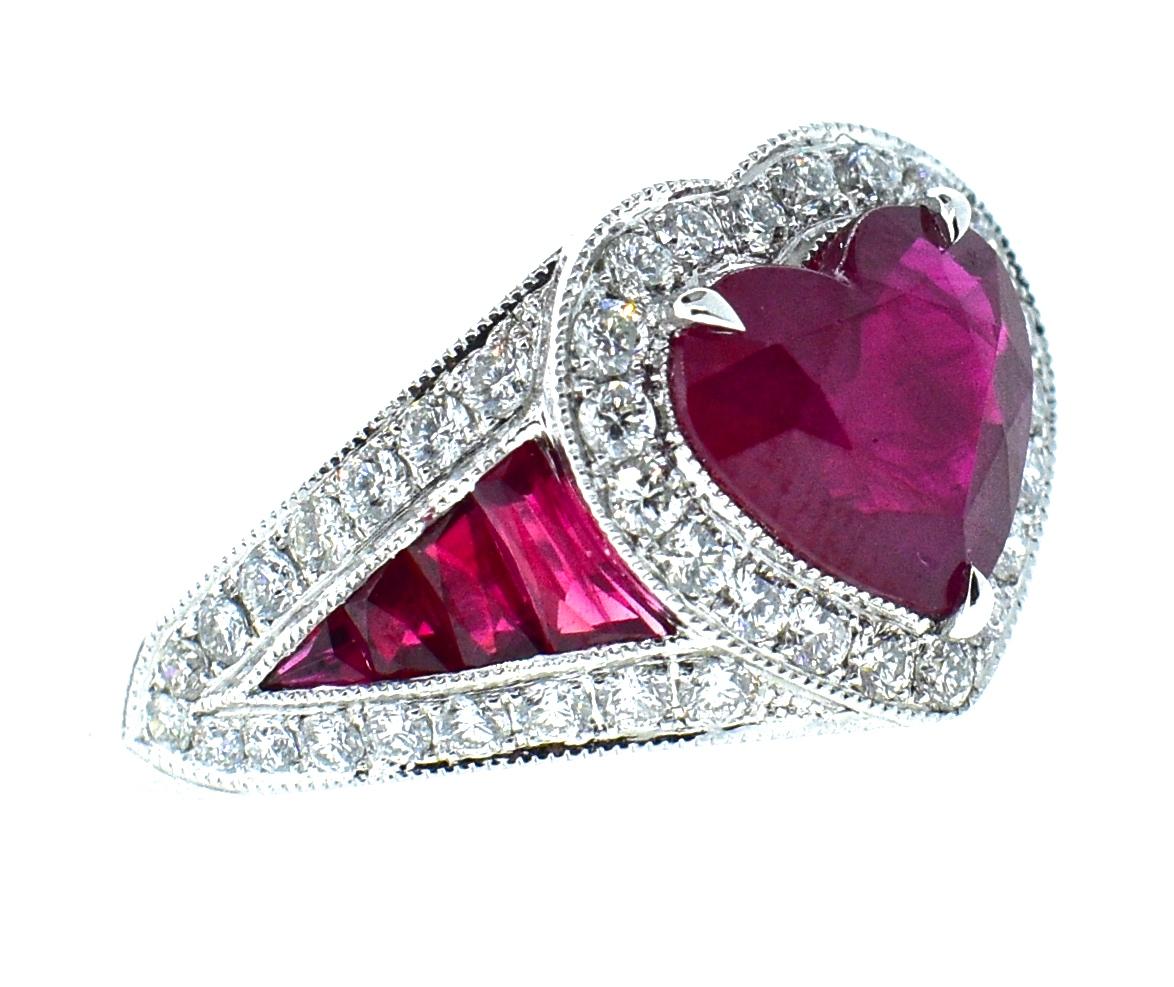 Natural bright red ruby in a heart shape is surrounded by white diamonds with matching fancy cut rubies going down the sides.  The fine center prong set red natural ruby weighs 3.67 cts., and the accent rubies weigh .70 cts., with a total ruby