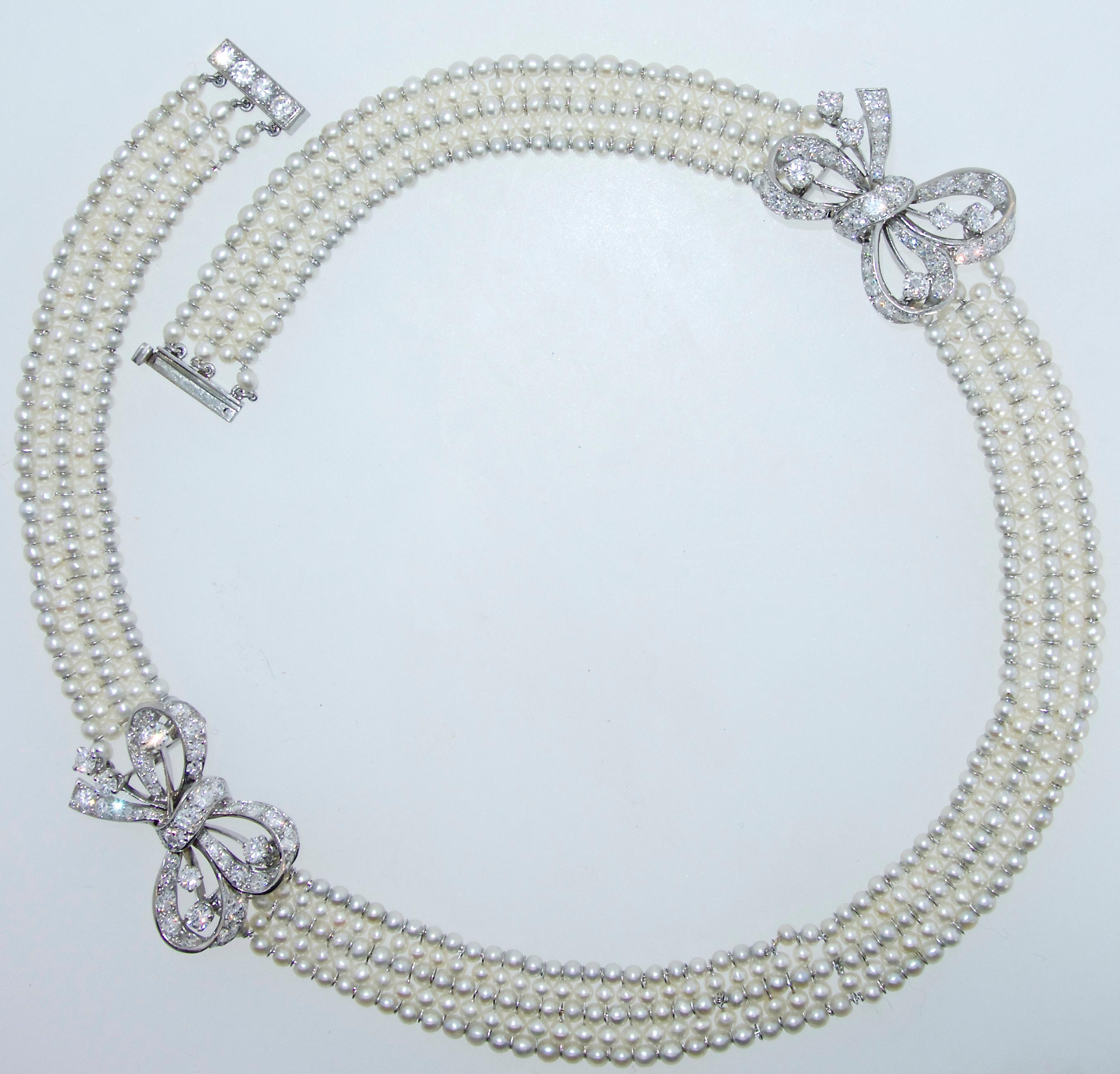 Natural pearl necklace accented with platinum and diamond bows and finished with a diamond and platinum clasp.  This collar necklace is 14 inches long.  The five strands of natural pearls are strung on platinum and have a wonderful luster.  The 86