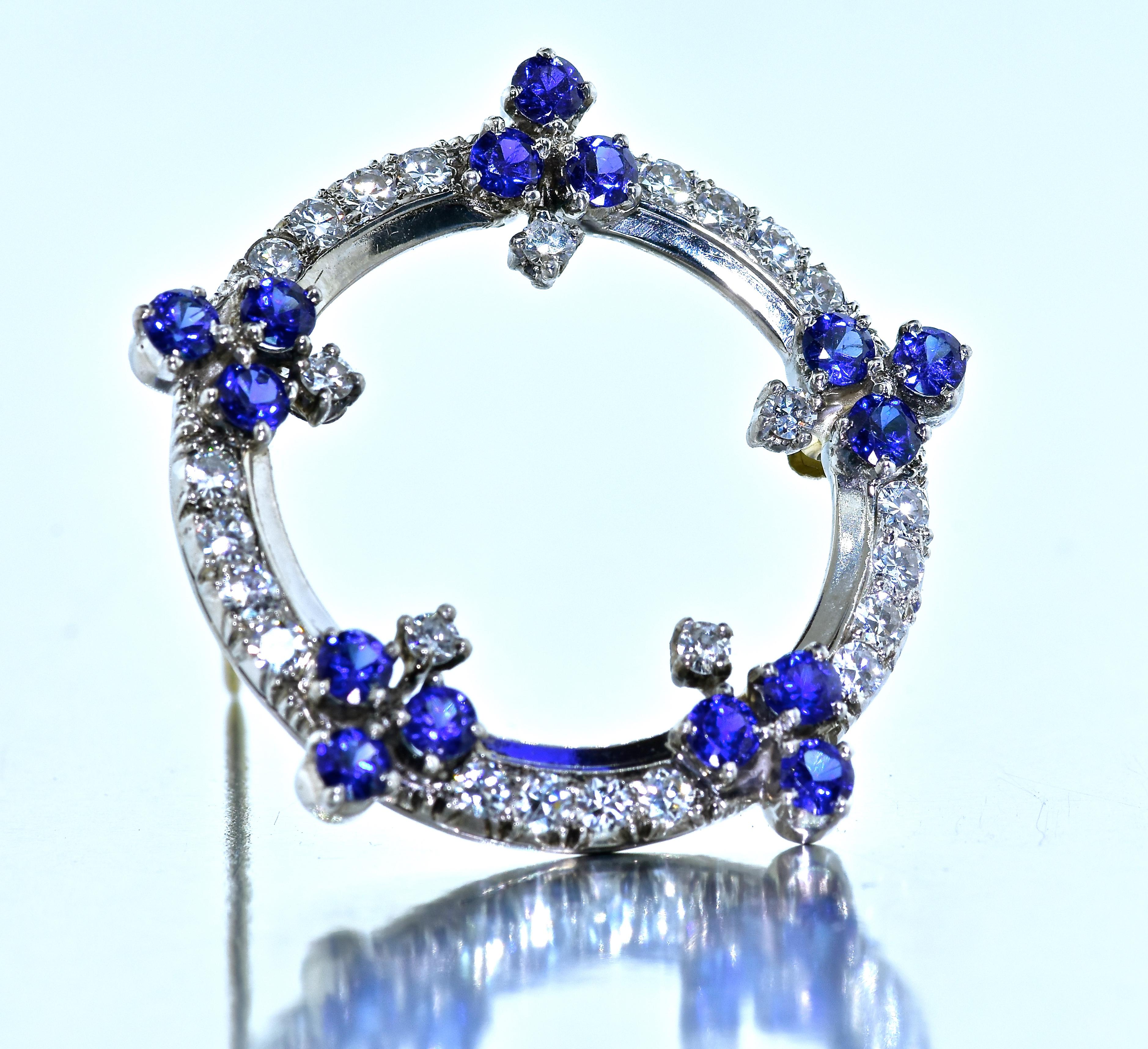 Platinum, diamond and sapphire brooch with fine white brilliant cut diamonds and 15 natural sapphires displaying vivid blue color and weighing an estimated 1.10 cts.  The diamonds are all well matched, with fine symmetry, color and clarity.  The 25