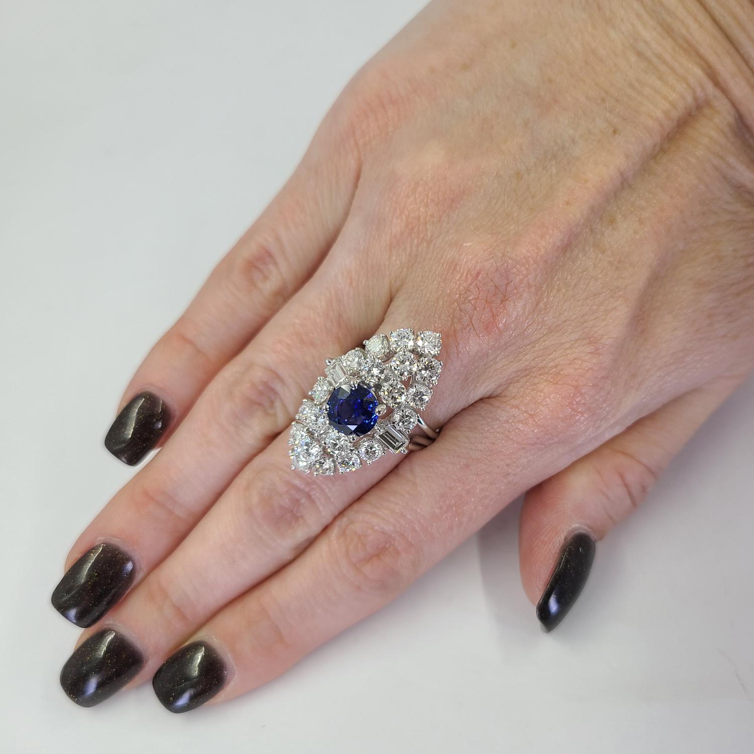Platinum Vintage Dinner Ring Featuring A 2.00 Carat Round Sapphire Accented By 22 Round & Baguette Cut Diamonds Of VS Clarity & G Color Totaling Approximately 3.50 Carats. Finger Size 6; Purchase Includes One Sizing Service. Finished Weight Is 13
