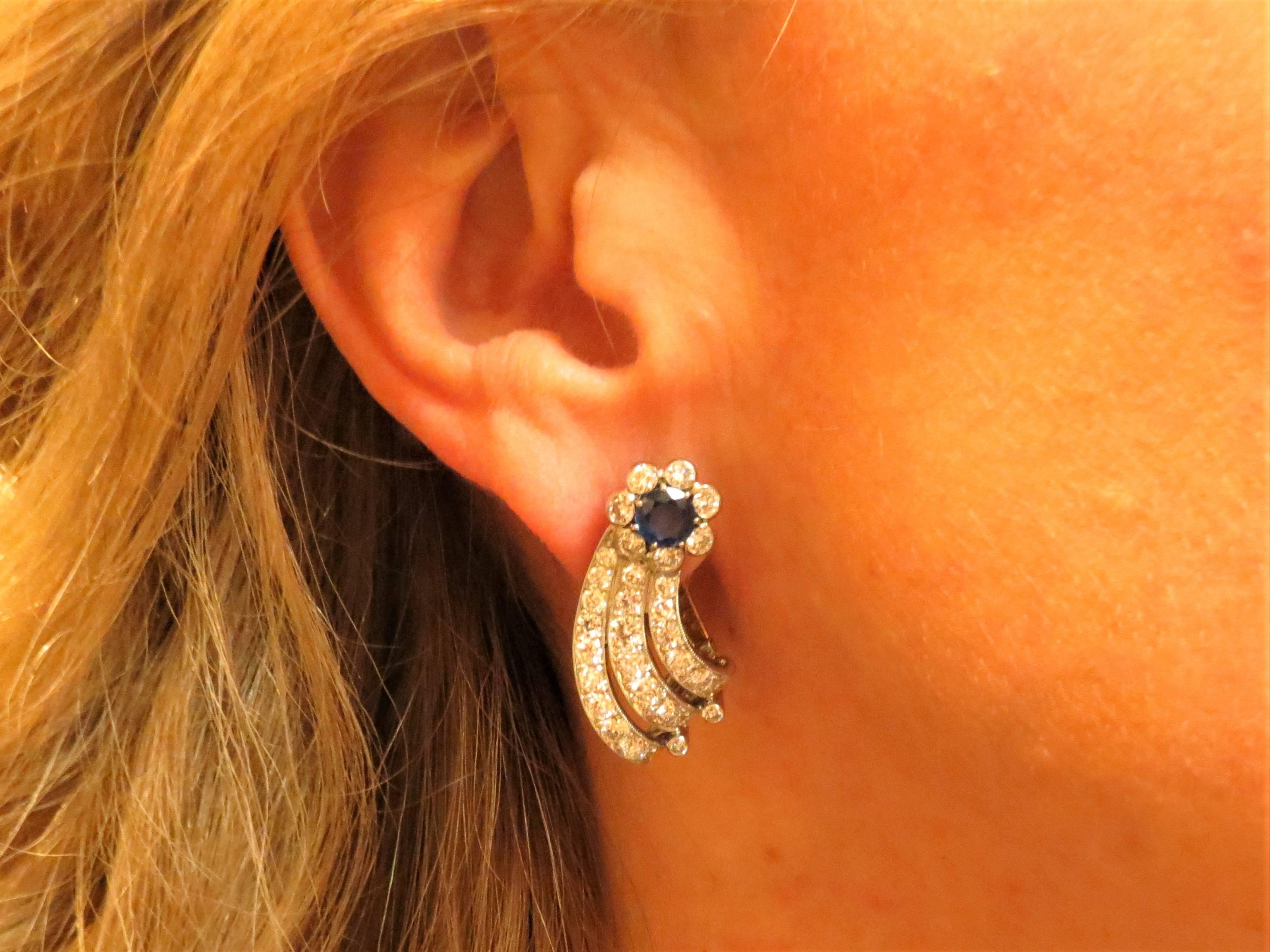 Platinum  ear clips prong set with two round faceted blue sapphires weighing 1.30cts and 64 full cut round diamonds weighing 3.50cts, G-H color, VS clarity, with 14K yellow gold clip back.