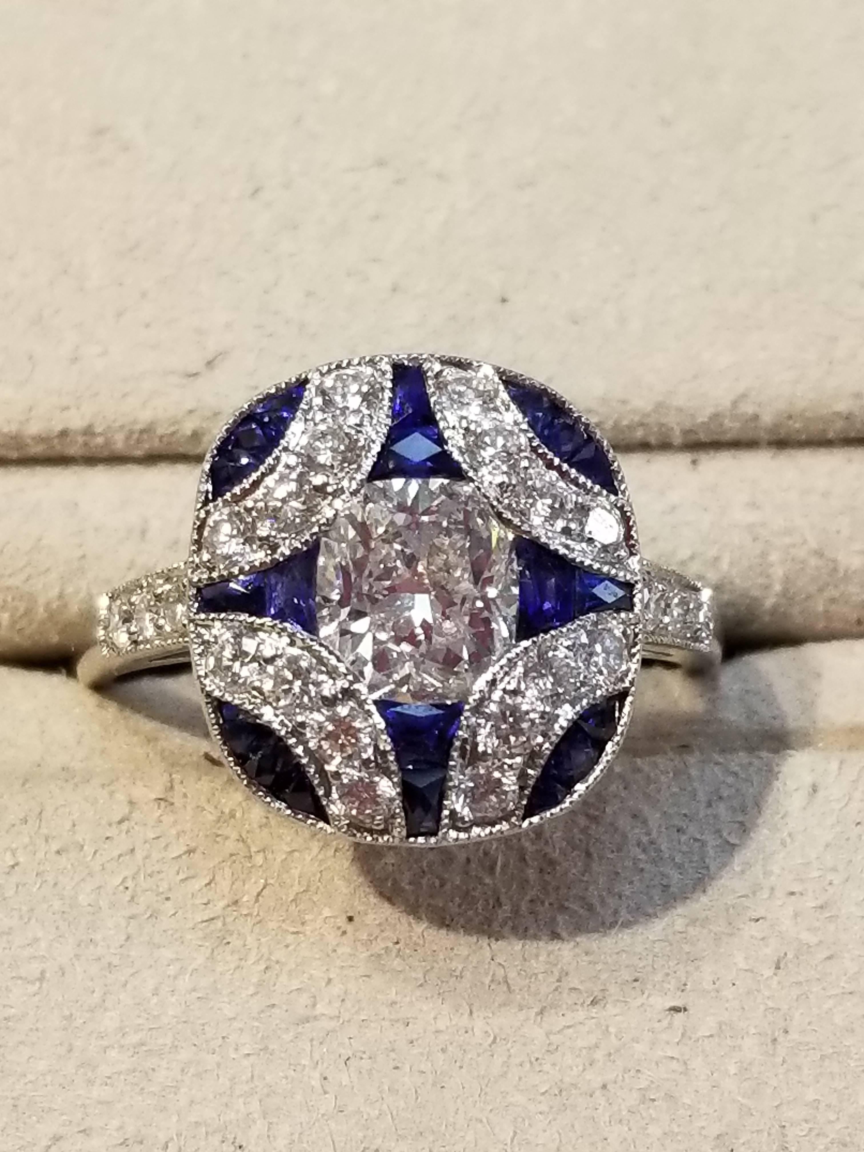 Platinum diamond and sapphire ring, size 6 1/2. The center diamond weighs 1.05 carats and the surrounding diamonds weigh 0.52 carats and are of FG color and VS1 clarity. The sapphires weigh a total of 1.36 carats. Art Deco style.