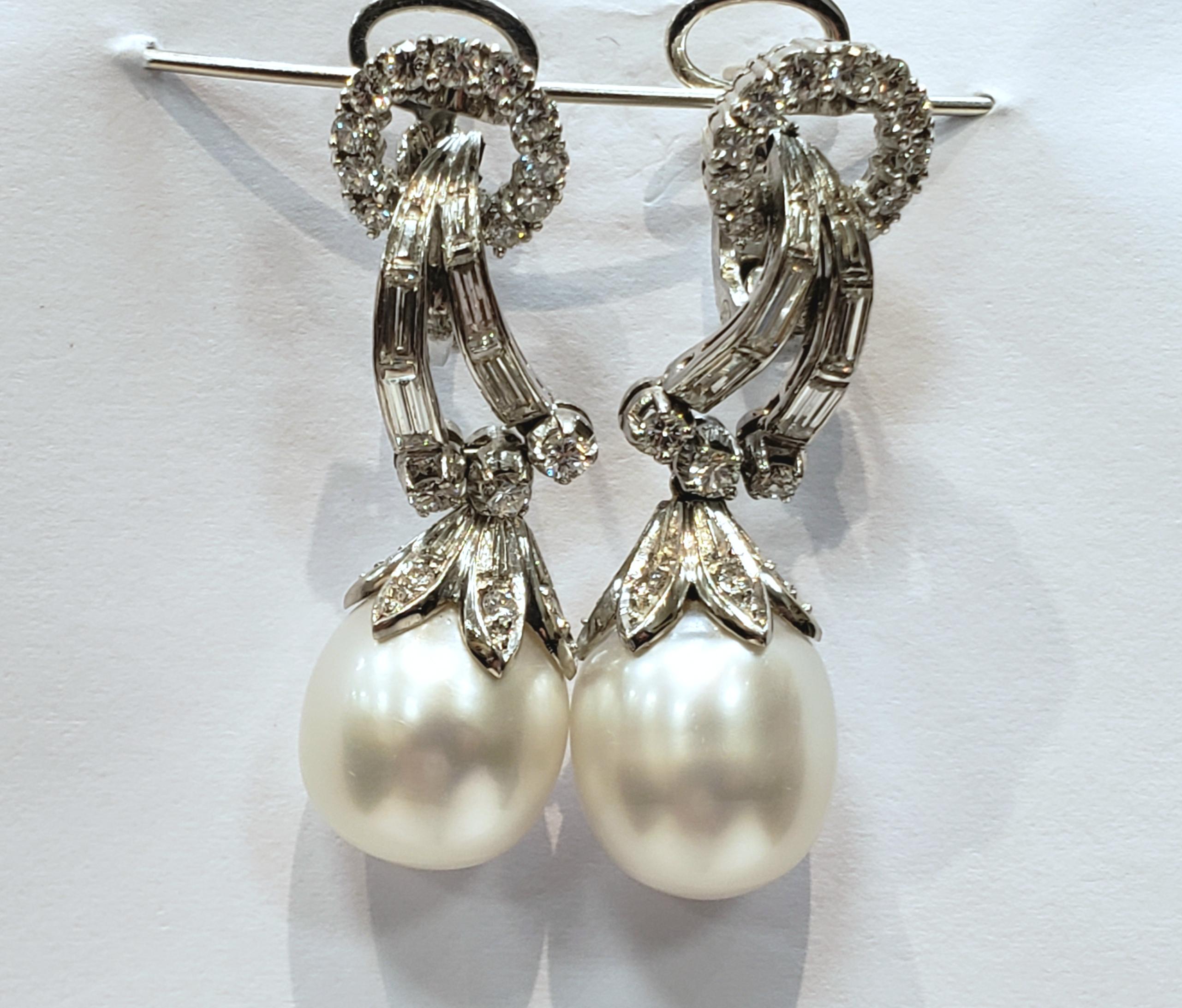Elegant Platinum, Diamond and South Sea Pearl Drop Earrings.
Each earring has a circle of small round diamonds, with a double row of cascading baguettes, followed by three round diamonds, a platinum cap and a white oval South Sea pearl. Earrings