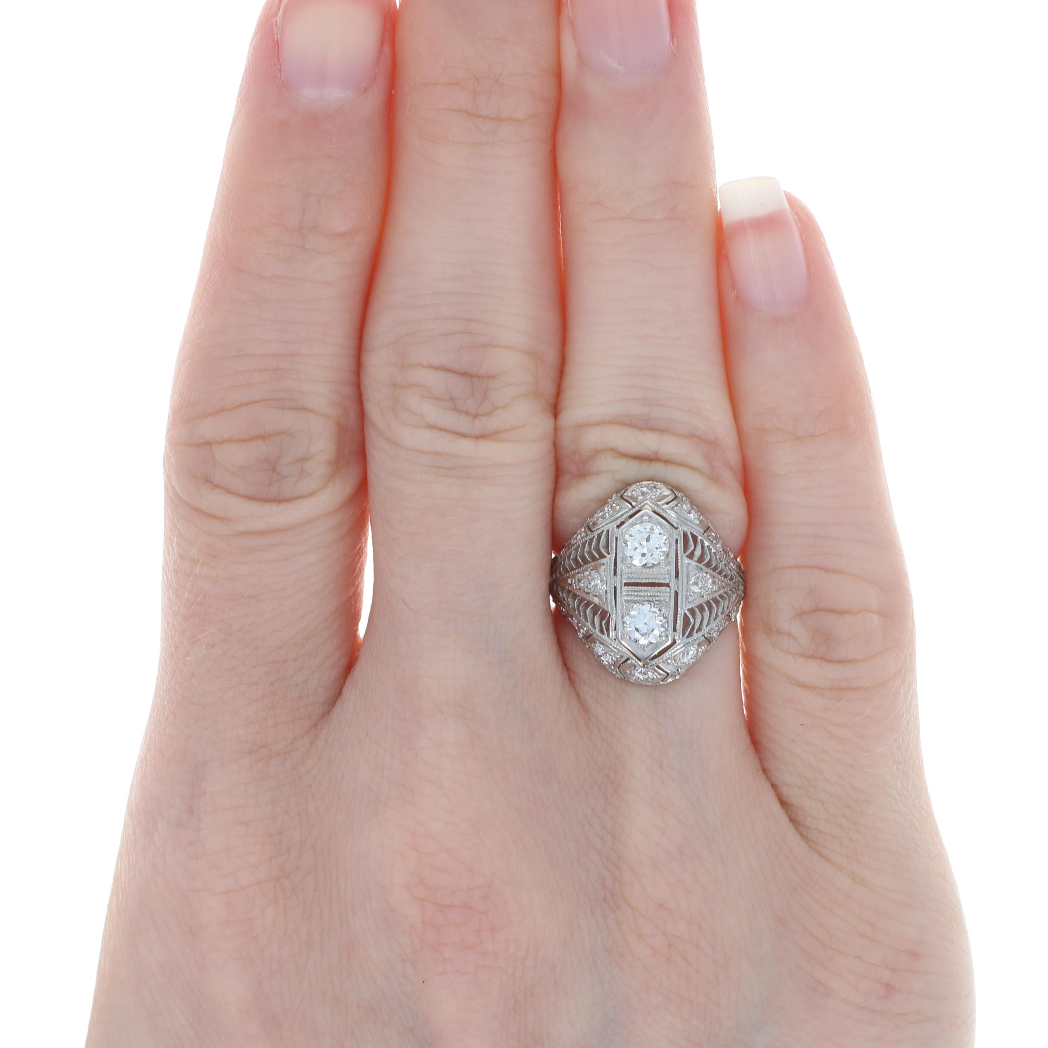 Art Deco allure! Exquisitely crafted in platinum, this glamorous vintage ring showcases an ornate filigree design featuring two European cut diamonds sweetly accompanied by a shimmering array of European cut and single cut accent diamonds. 

This