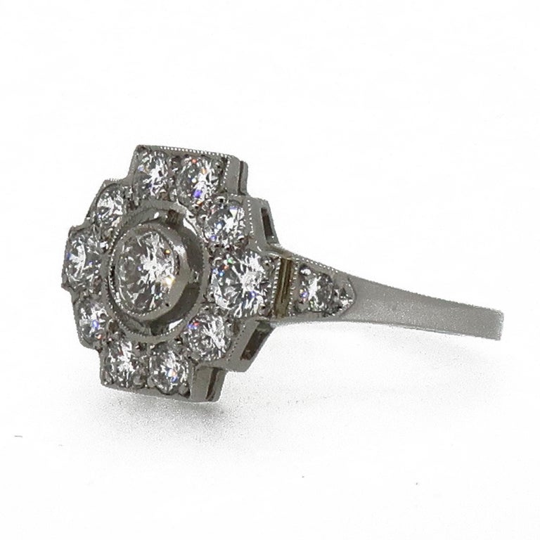 Platinum Diamond Art Deco Style Cluster Ring

A dazzling Art Deco style diamond cluster ring. Central white brilliant cut diamond in an open mill-grain bezel, bordered by ten brilliant cut diamonds, with a further diamond on the top of the