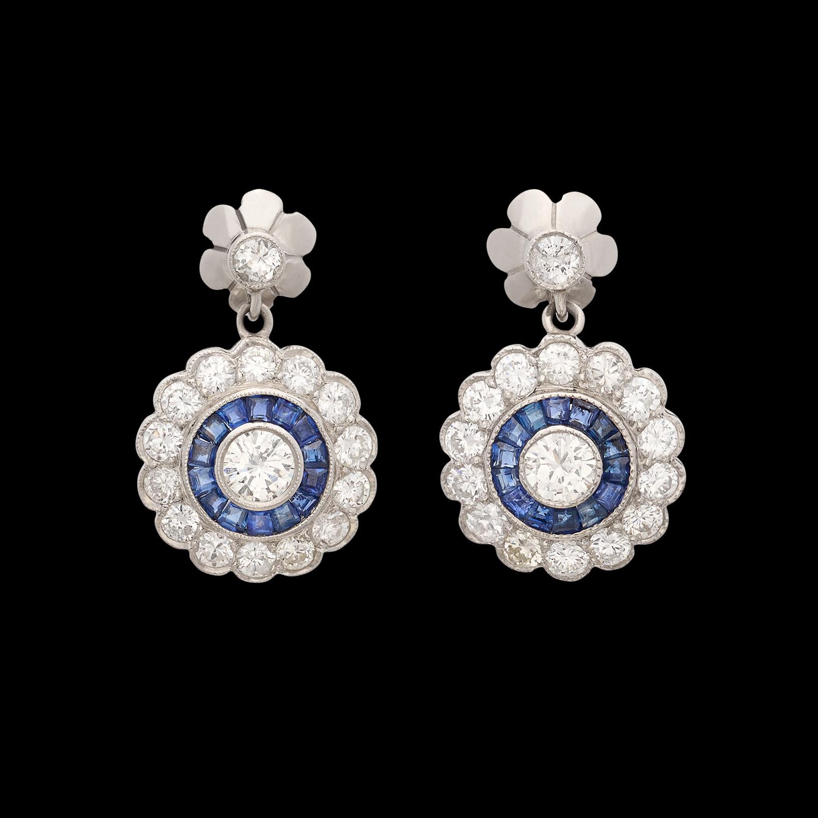 Sophisticated style at its finest. These platinum earrings feature at the center two perfectly matched round brilliant cut diamonds weighing 0.50cttw surrounded by a thin halo of sapphires, along with a larger diamond halo featuring 30 additional