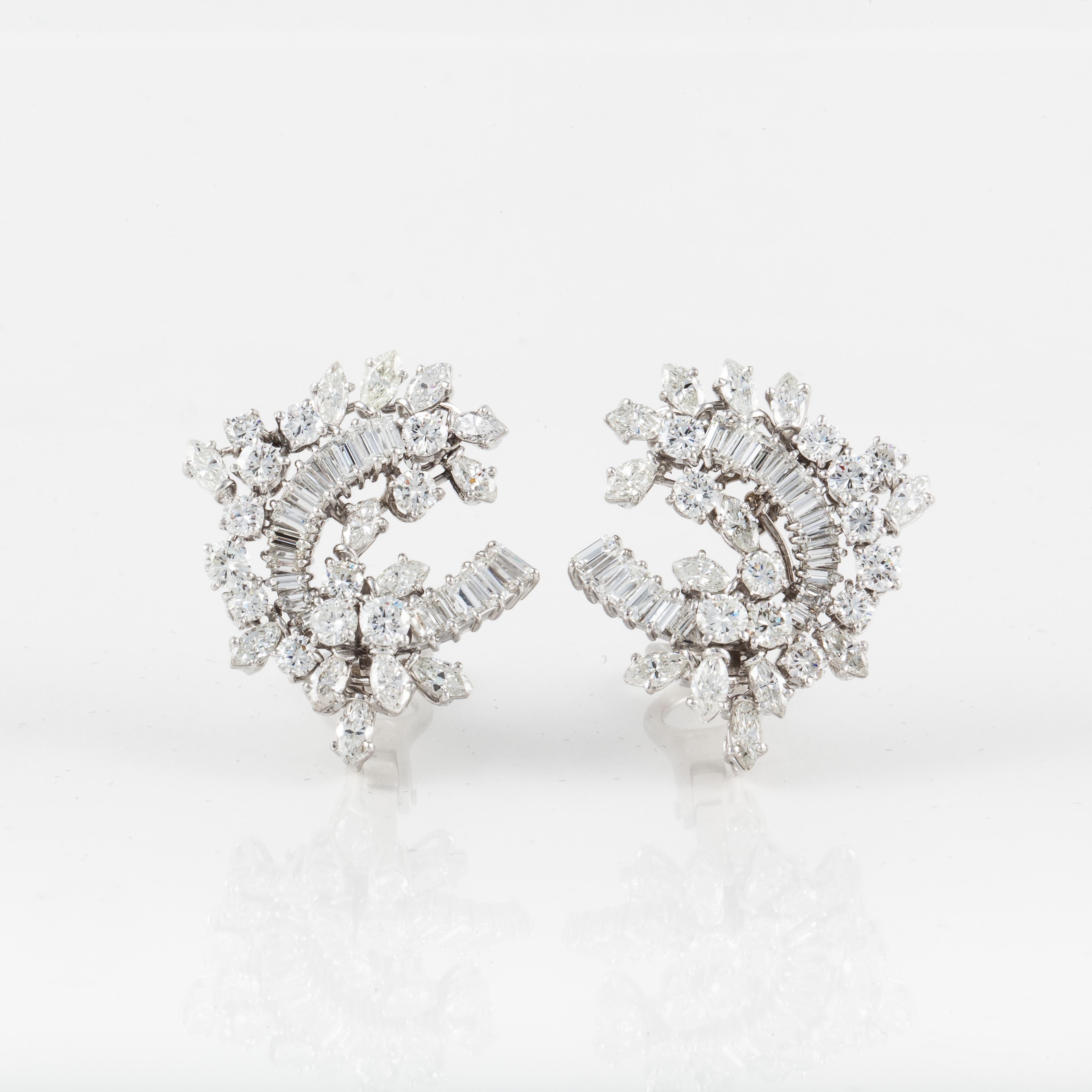 1950s platinum diamond cluster earrings featuring a stylized open frame floral design centrally set with 36 baguette-cut diamonds framed with 24 marquise and 22 round brilliant-cut diamonds that total 9.50 carats. The diamonds are G-I color and