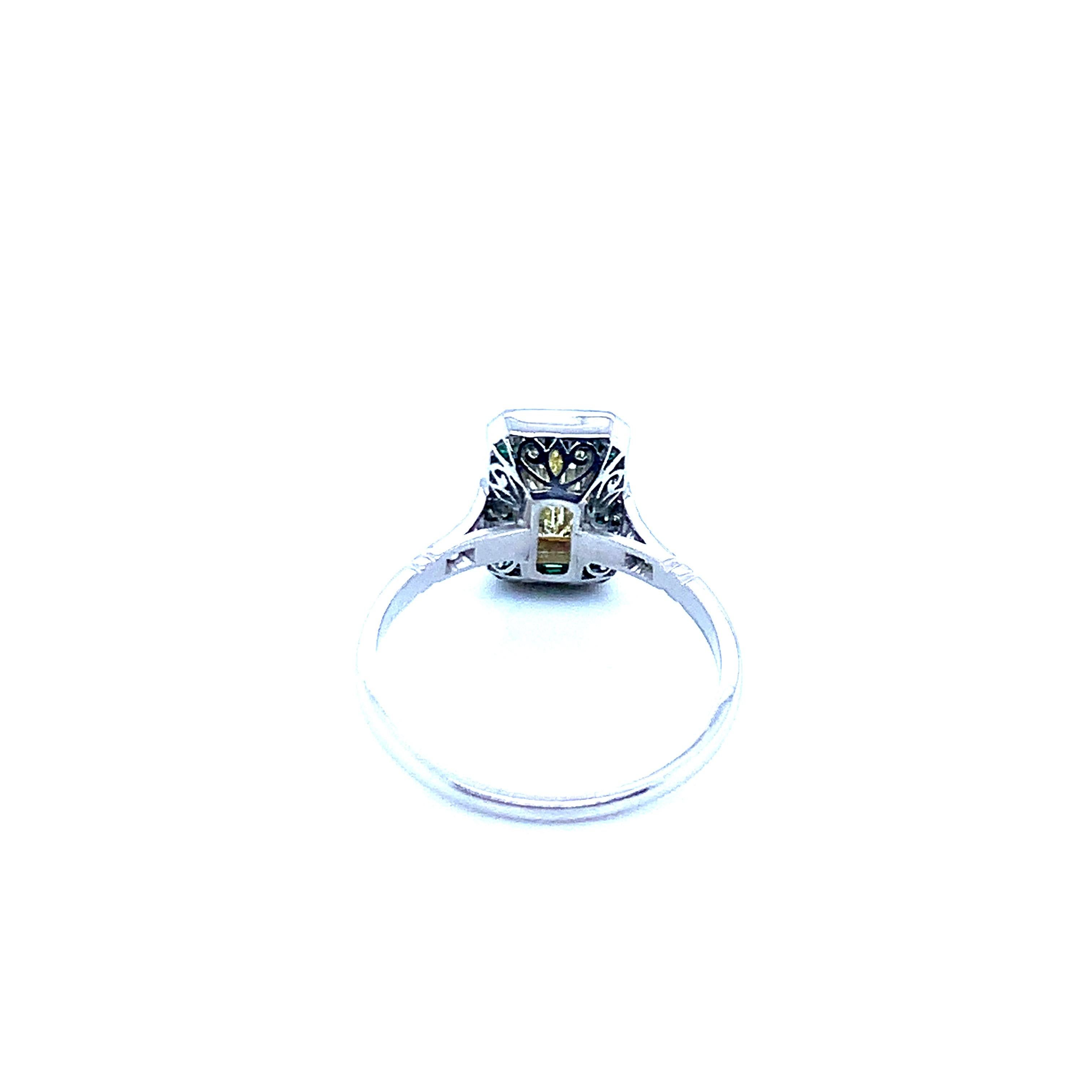 Platinum ring with one baguette cut diamond that weighs 0.71 carat, 6 old mine cut diamonds that weigh 0.09 carat, and 22 emeralds that weigh 0.55 carat. An art deco recreation, this ring weighs 3.6 grams. Size 7.25.