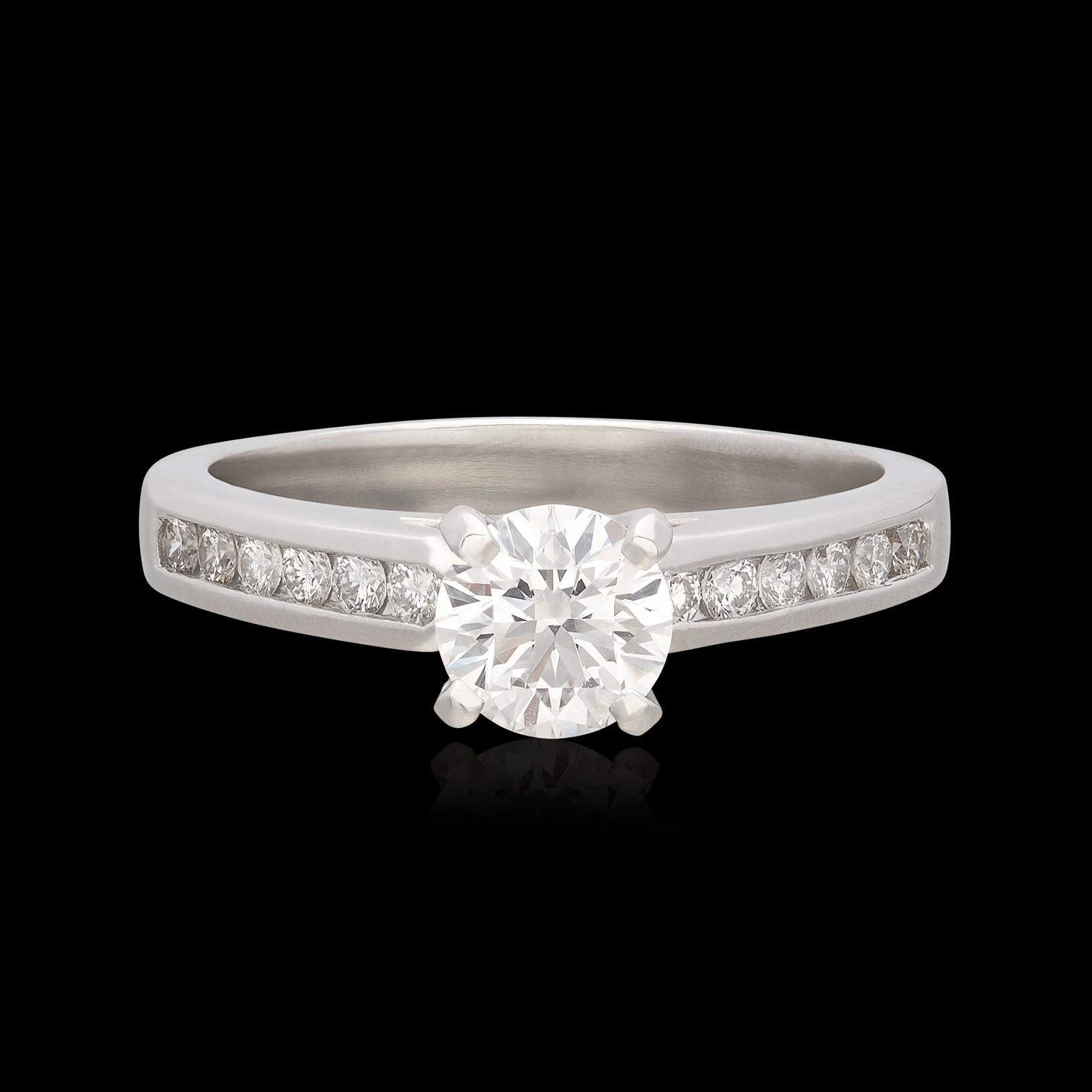 With great brilliance and flash, this platinum engagement ring shines far beyond it's size, It features a round brilliant-cut diamond weighing approximately 0.72ct., with a grading of G/VS, accented with rows of 12 round diamonds channel-set down