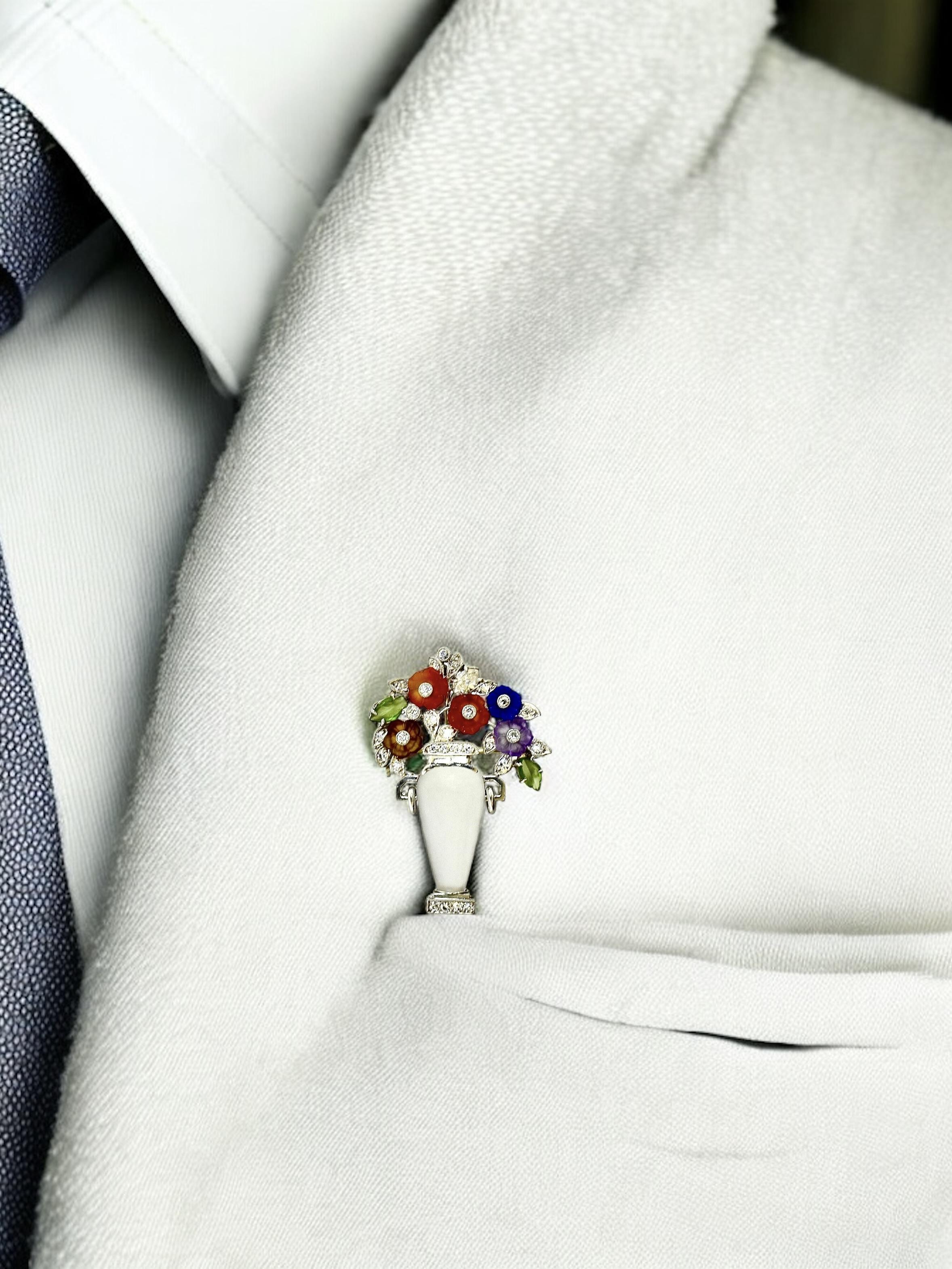 Platinum, diamond, frosted rock crystal and carved hard stones depicting leaves and budding flowers in a vase, this brooch can also be worn as a pendant with the flip up bale. Chain shown is for photography only and is not included, but can be