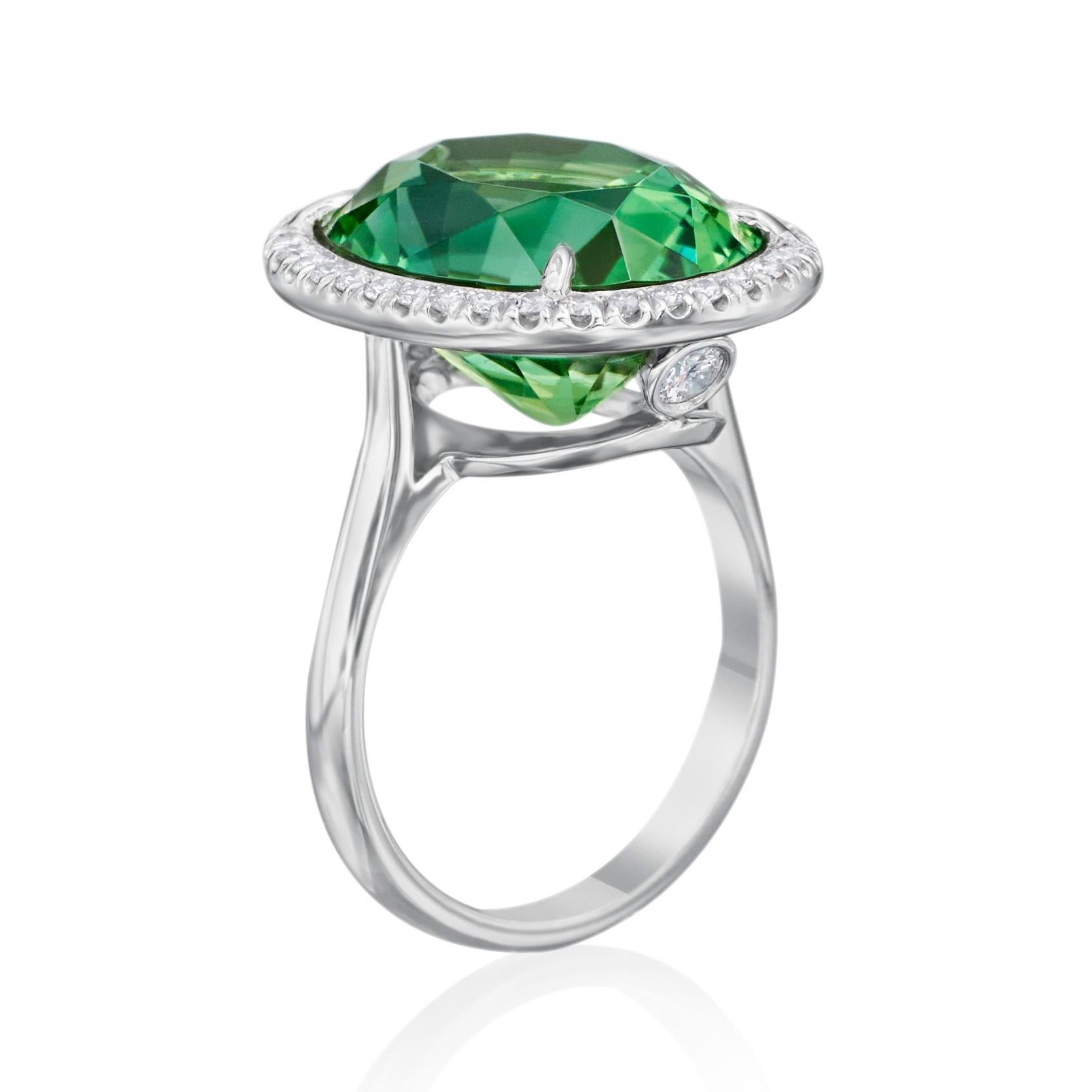 Complement her daring and lovely personality with the breathtaking color and classic halo design of this remarkable gemstone and diamond ring. Stunning in platinum, this extraordinary 10.55 carat oval faceted green Tourmaline is surrounded by 36