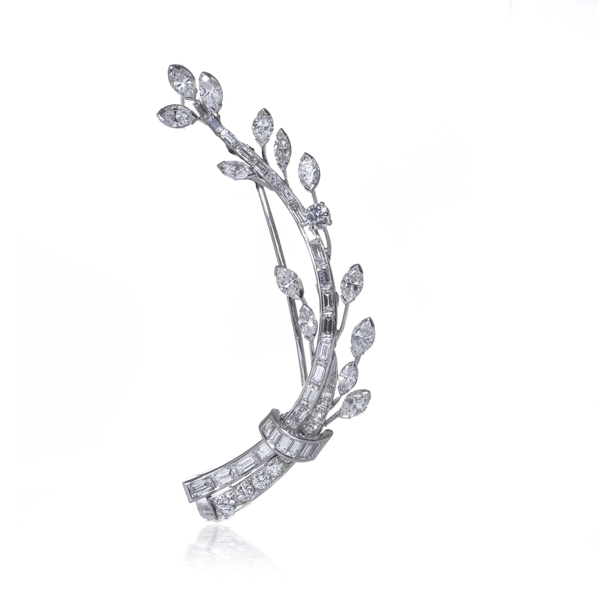 Un'elegante spilla di diamanti in platino disegnata come un getto di foglie stilizzato, con diamanti taglio marquise, baguette e tondo brillante incastonati. Il design fluisce con grazia grazie alla combinazione di forme geometriche e organiche,