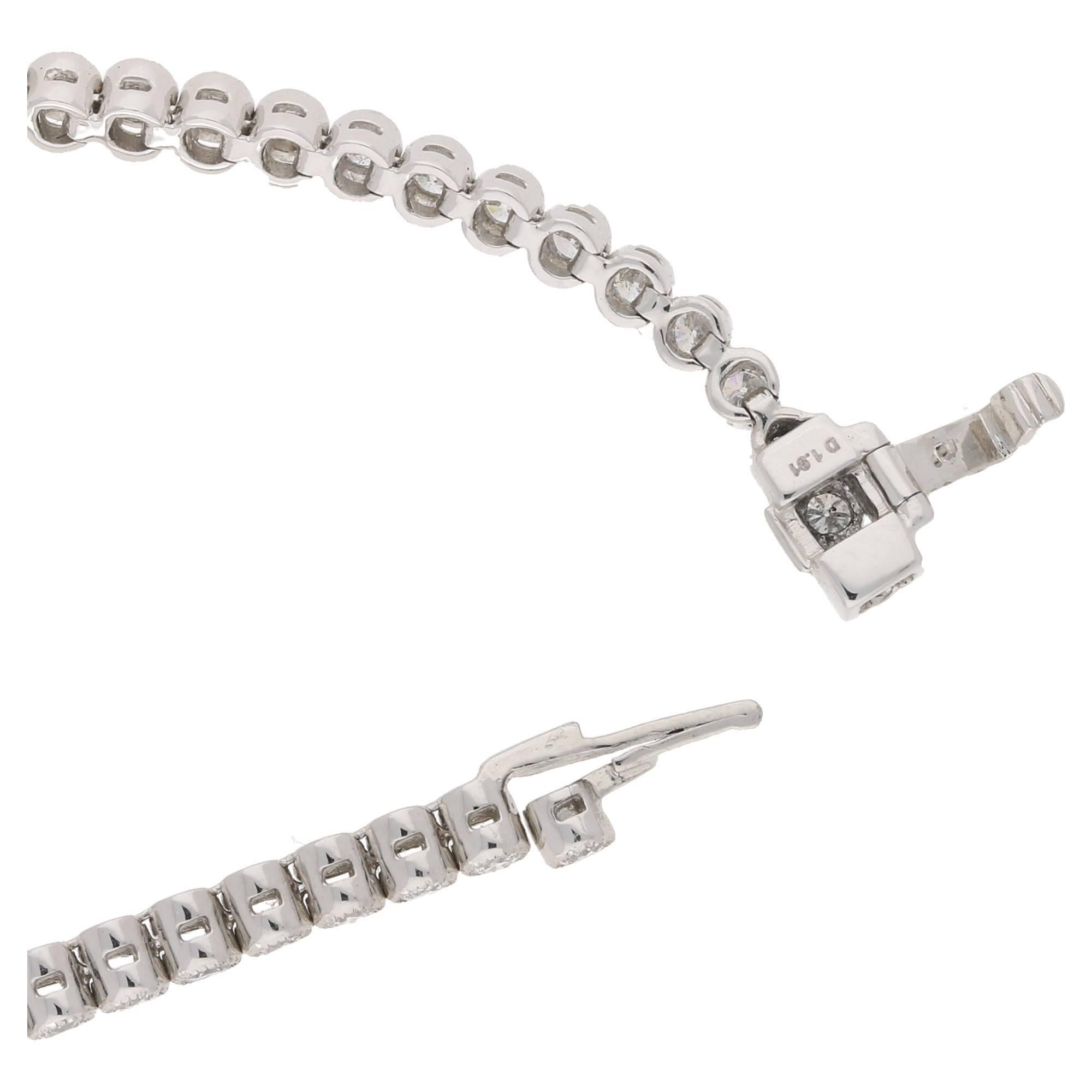 A platinum and diamond line bracelet. The bracelet is formed of seventy five round brilliant cut diamonds each in a spectacle setting with a millegrain finish. The bracelet is fitted with a tongue piece clasp with a under arm safety catch. Total