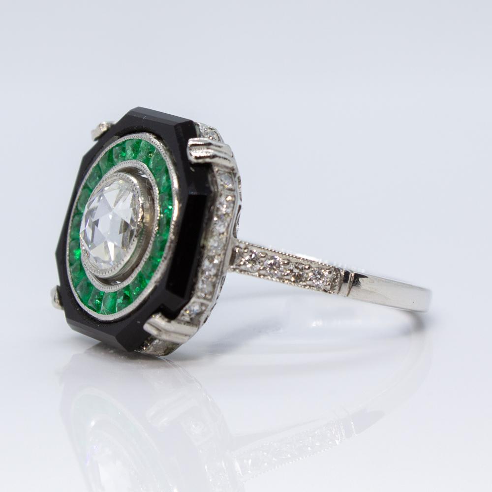 Composition: Platinum
Stones:
•	1 Rose cut diamond of I-SI1 quality that weighs 0.75ctw.
•	32 Old European cut diamonds of H-VS2 quality that weigh 0.50ctw. 
•	20 natural French cut emeralds that weigh 0.50ctw.
•	1 natural onyx.
Ring size: 6 
Ring