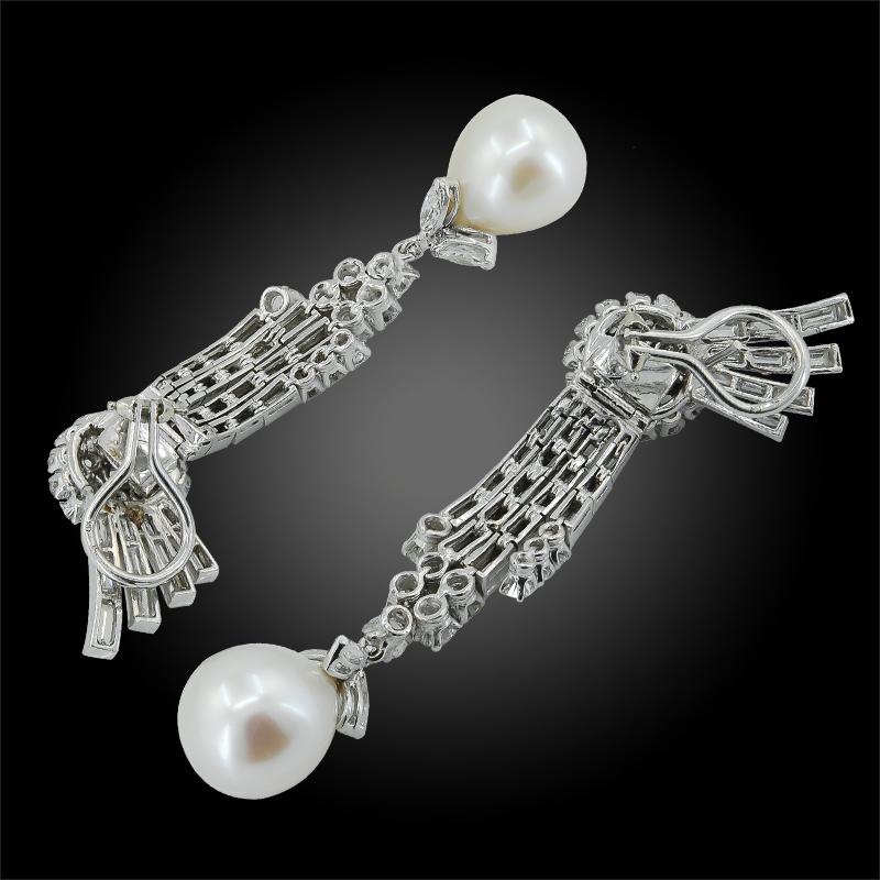 Un paio di orecchini pendenti degli anni Sessanta in platino, diamanti e perle, che emanano un'eleganza senza tempo e un'eterna raffinatezza. Ciascuna clip per orecchie misura 2,75 pollici di lunghezza e presenta un'impressionante perla di 12,00 mm