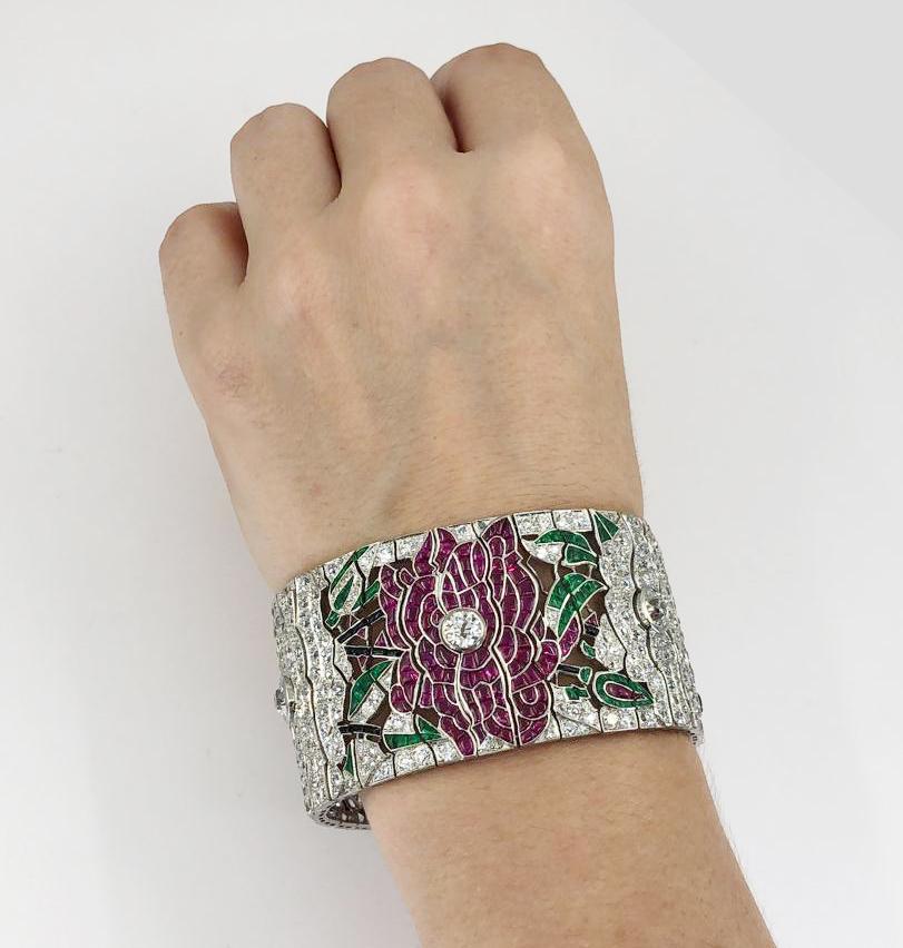 Platinum Diamond, Ruby, Emerald & Onyx Flower Wide Bracelet.

Diamond weight is approx. 22.50 carats total. Ruby weight approx. 36.14 carats total. Emerald weight approx. 7.45 carats total. Measures approx. 1.37″ in width by 7.25″ in length, with an