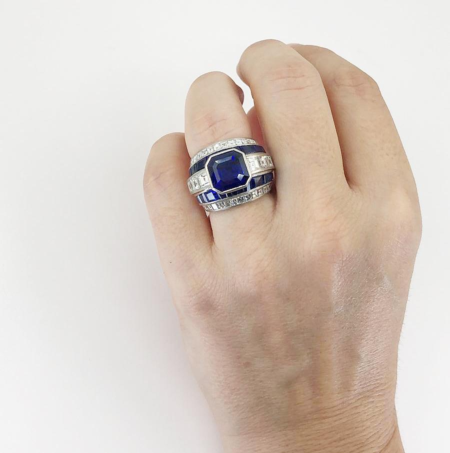 Contemporary Sapphire Diamond Ring 5.08 cts in Platinum.

A contemporary dome-shaped ring with an intense Asscher / Square Emerald Cut blue sapphire surrounded by calibré-cut matching gemstones. In addition, the ring includes calibré bright white