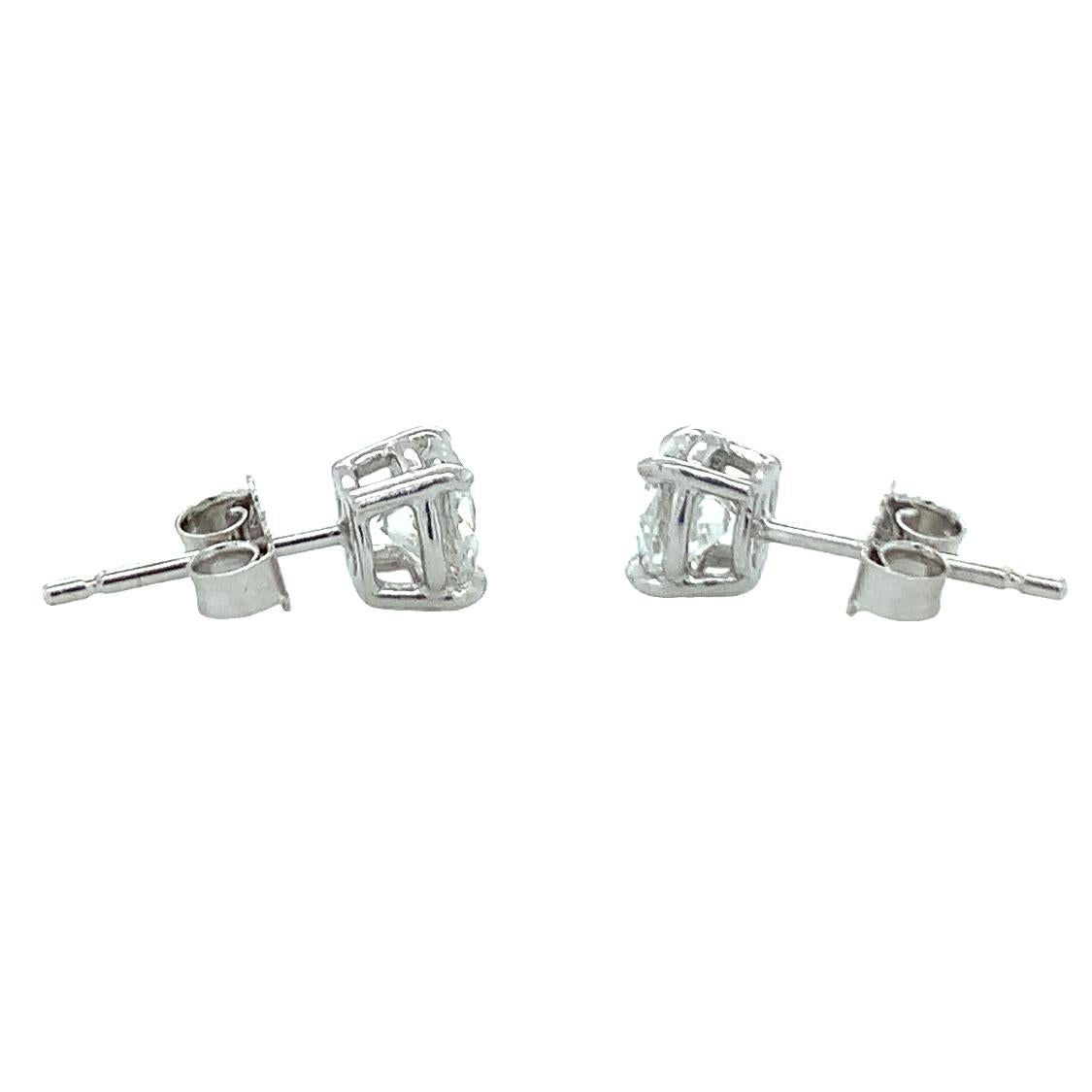 One pair of platinum diamond stud earrings featuring two prong set, round brilliant cut diamonds totaling 1.10 ct. total weight (0.56 ct., E / VS-1 + 0.54 ct., F / VS-1 with GIA E-Reports). Featuring push back backings and weighing 2.6 grams in