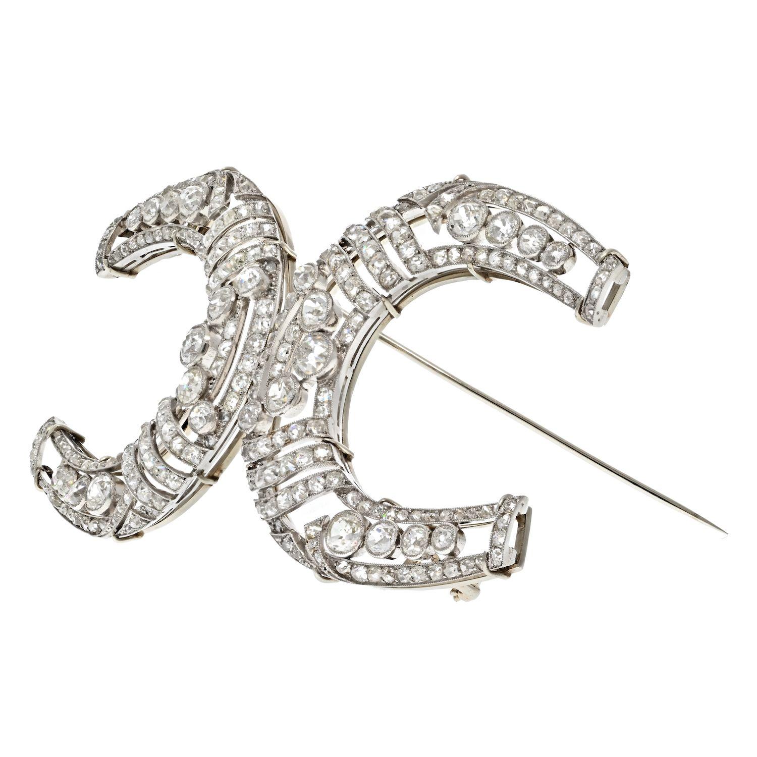 Platinum Double Horse Shoe Vintage Brooch. Mounted with 23 carats of antique diamonds over filigree frame. The brooch has a beautiful open layout made in a shape of a double horse shoe connected in the middle. The diamonds are of a nice light warm