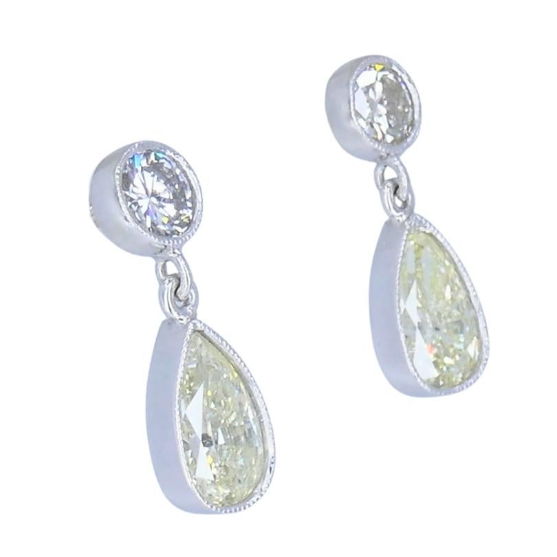 Une paire de boucles d'oreilles raffinées en platine avec deux formes de diamants qui se complètent l'une l'autre. Chaque boucle d'oreille présente un diamant poire d'environ 1,05 carat suspendu à un diamant rond de taille brillant d'environ 0,40