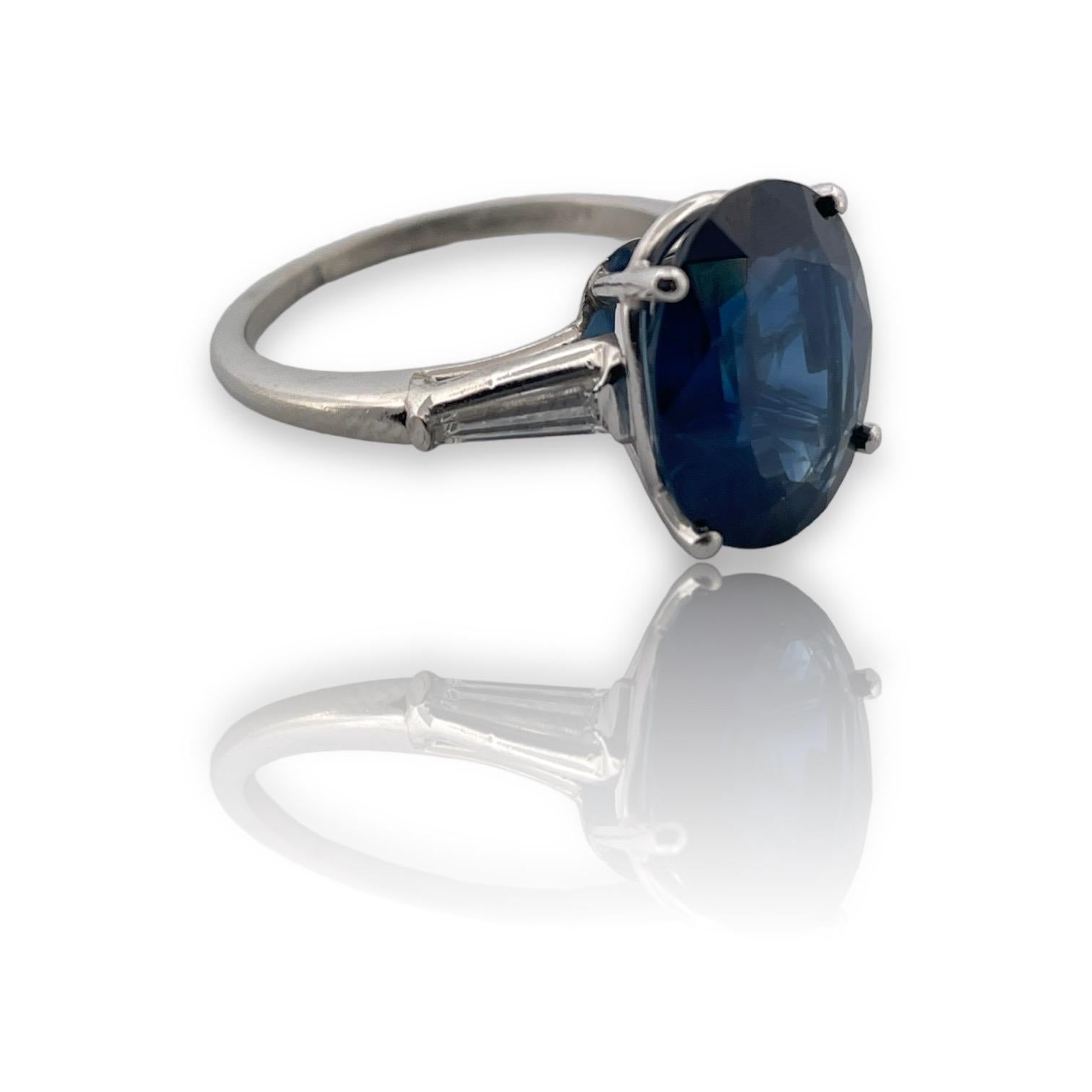 Featuring a majestic 6.12 ct oval cut sapphire, certified by GIA for its heat-only enhancement, this size 7 platinum band is adorned with two elongated tapered baguette diamonds. A true embodiment of grace and sophistication for the discerning