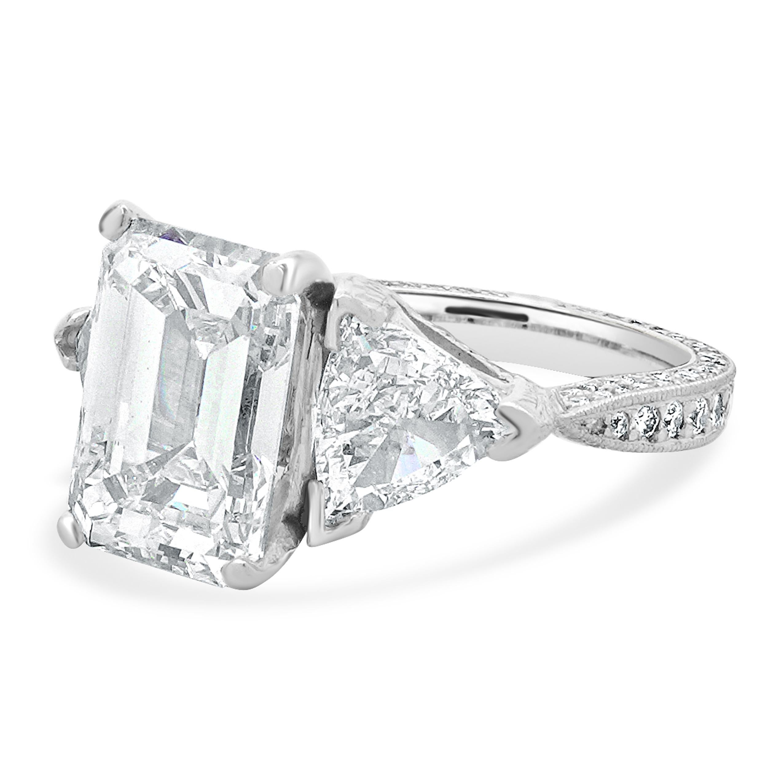 Material: Platinum
Center Diamond: 1 emerald cut = 5.03ct
Color: J
Clarity: SI1
GIA: 2235445185
Diamonds: 2 trillion cut = 1.76cttw
Color: G / H
Clarity: VS2-SI1
Diamonds: 66 round brilliant cut = 1.89cttw
Color: G 
Clarity: VS2
Ring Size: 5.75