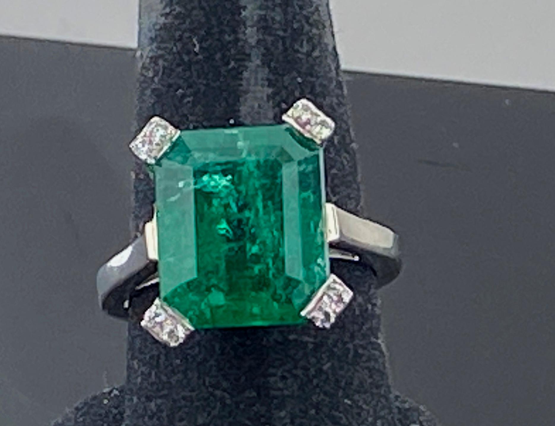 Set in Platinum is a 13.03 carat Emerald cut Emerald with 8 small round brilliant cut diamonds weighing 0.10 carats.  Color F-G, VS-1, Size 9.
