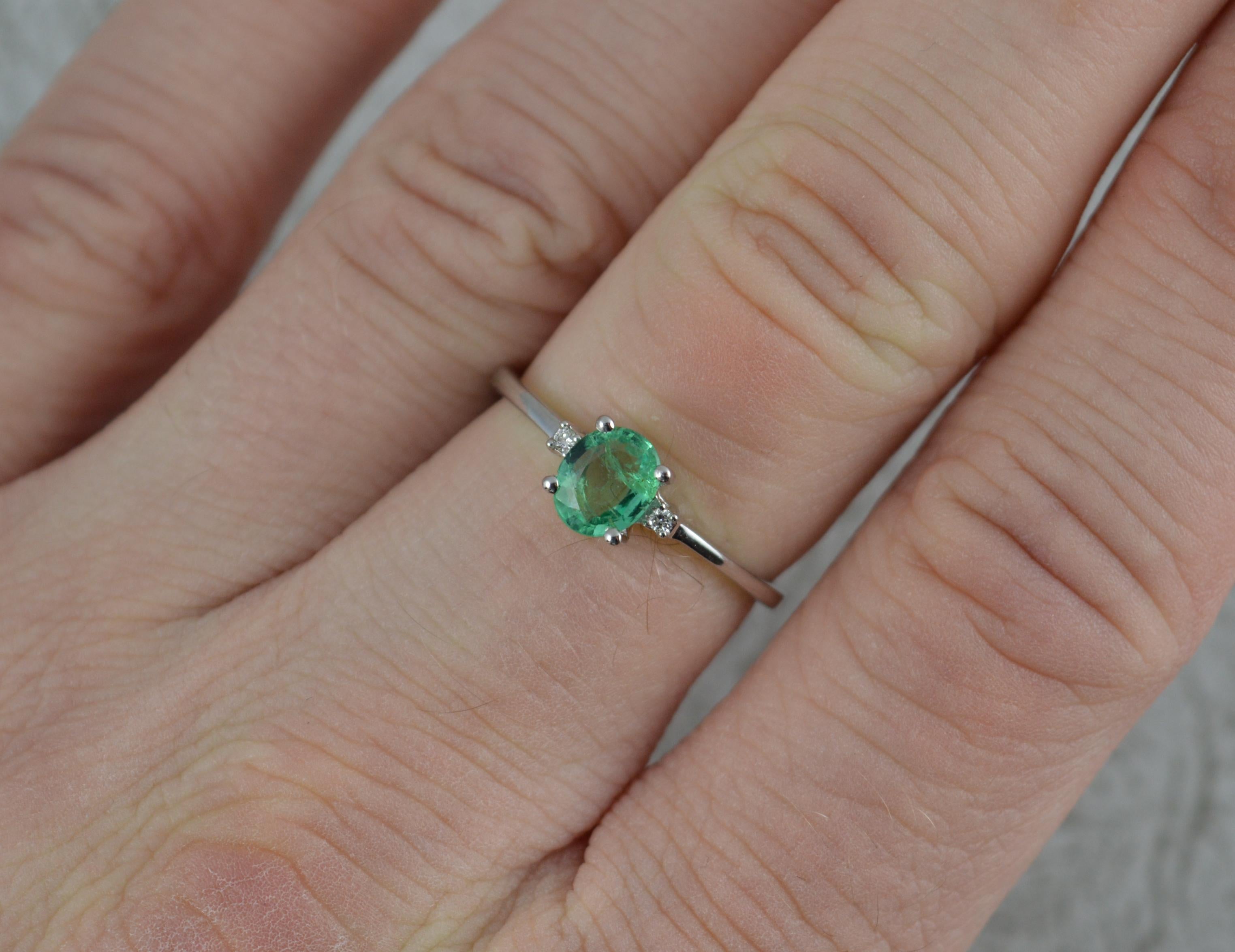 A stunning natural Emerald and Diamond ring.
Modelled in 950 grade platinum.
Designed with an oval emerald to centre in four claw setting. 5mm x 6mm. Set with a small round cut diamond to each side.
Zambian origin emerald.

Condition; Excellent.