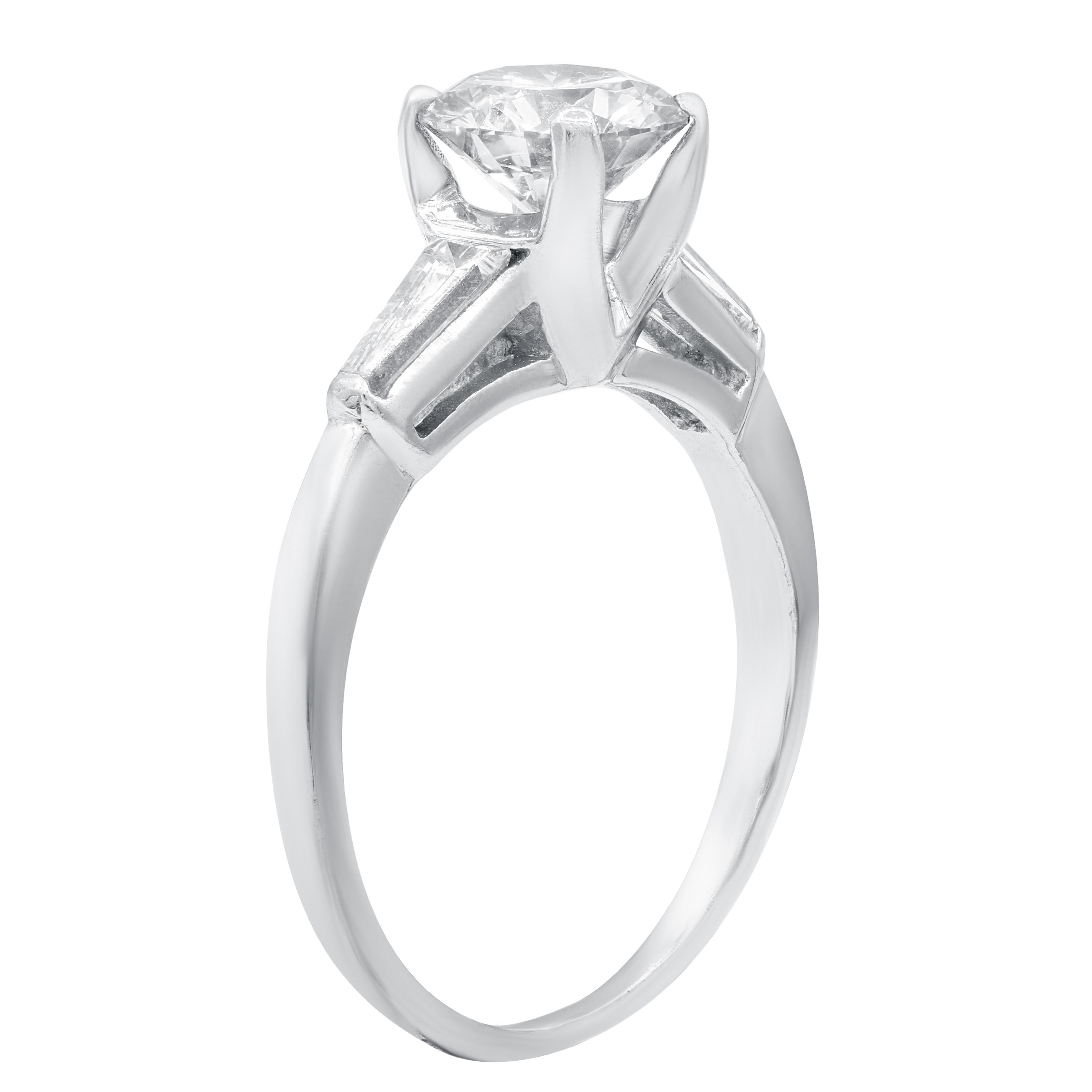 Platinum engagement ring features 1.03 carat of round diamond and .20 ct baguette on the sides.
