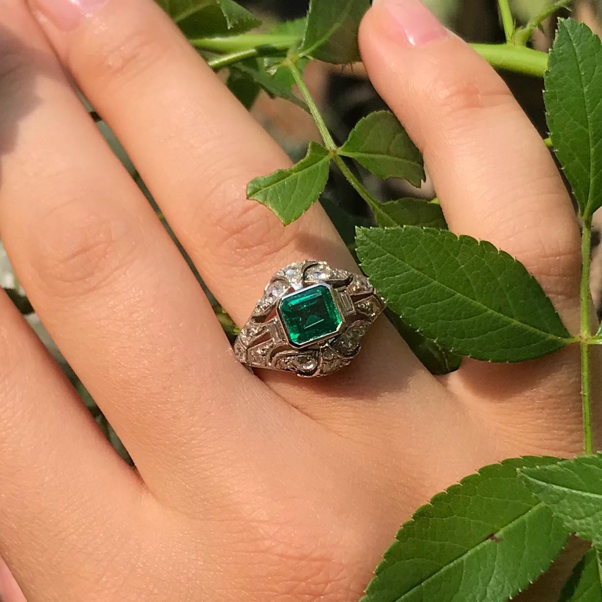 In this elegant platinum Estate engagement ring from 1920, the natural Colombian emerald emanates its verdant green colour over eight grand old mine brilliant cut diamonds and ten smaller old mine single brilliant cut diamonds. On the front and the