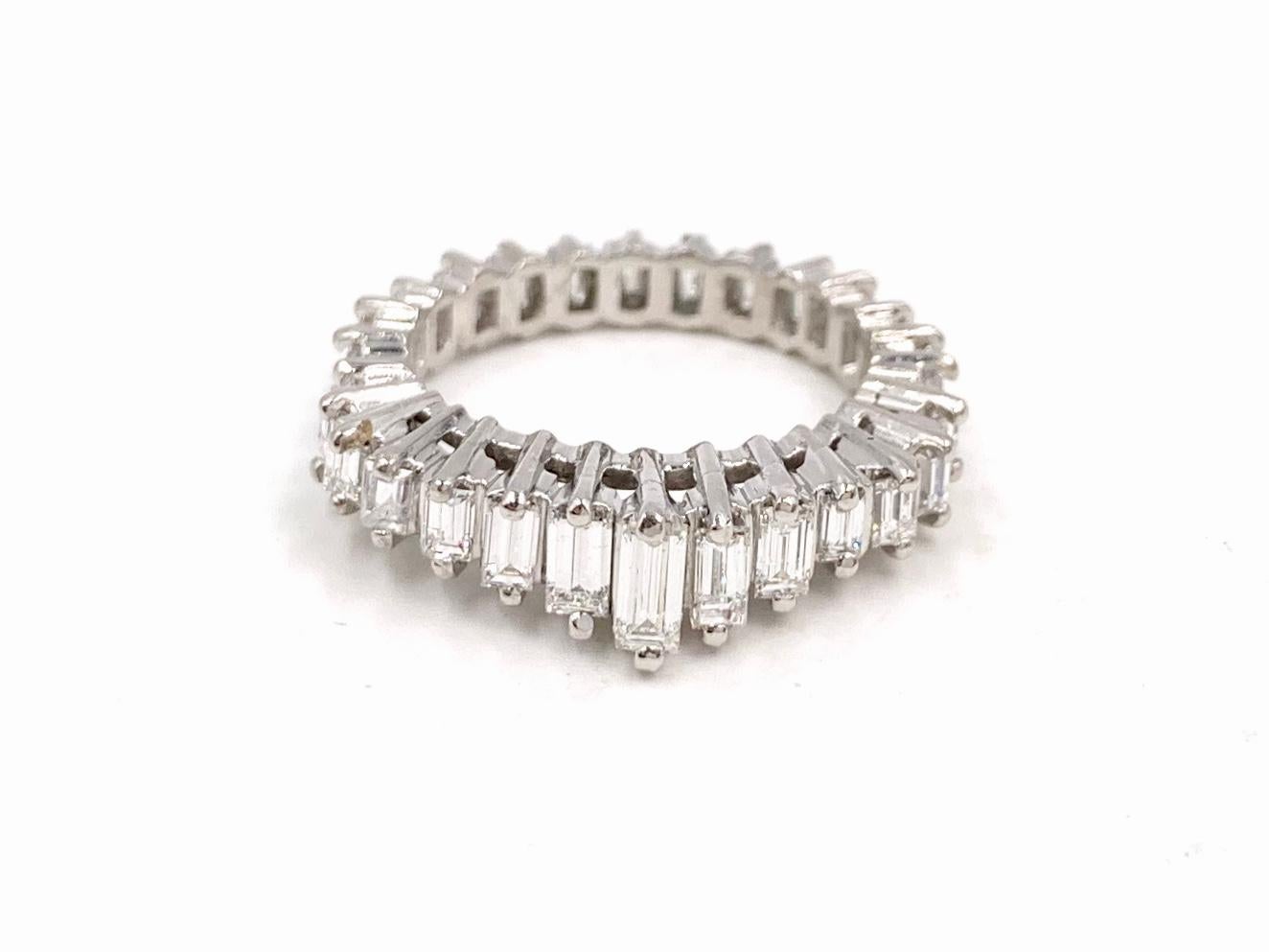 A fashionable and well made platinum eternity band featuring 1.79 carats of graduated  baguette diamonds. Diamond quality is approximately G color, VS2-SI1 clarity. Diamonds are set in individual baskets with a prong at north and south. Width of