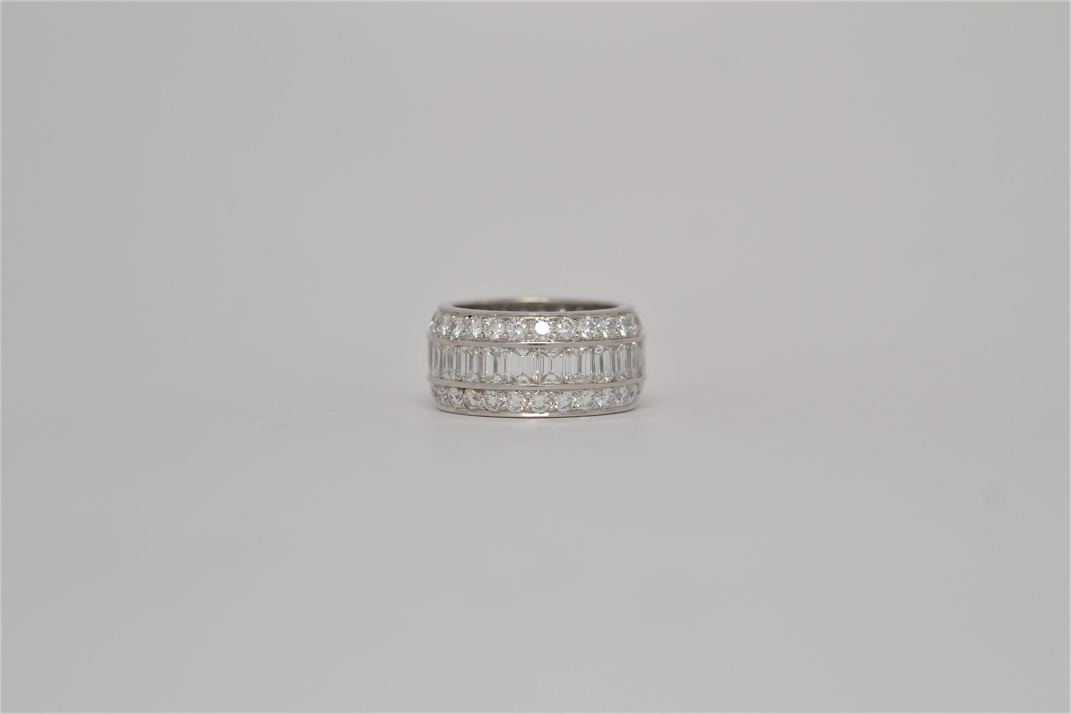 A unique three row Platinum and Diamond wedding band. The handmade Platinum ring is set all the way around with diamonds in an eternity style layout. A center row of channel set Emerald Cut Diamonds is accented by two rows of Round Brilliant Cut