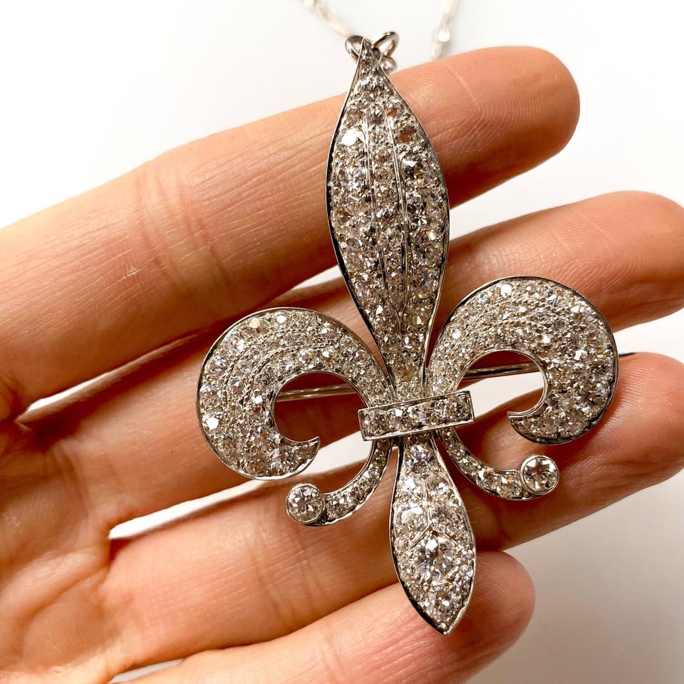 This pendant brooch is made in platinum and is neatly paved with old cut diamonds. 
The pendant brooch has the all classic Victorian Fleur Dis Le design and features glorious 14cts of old mine cut diamonds in a Fleur Dis Le  shaped burst of white