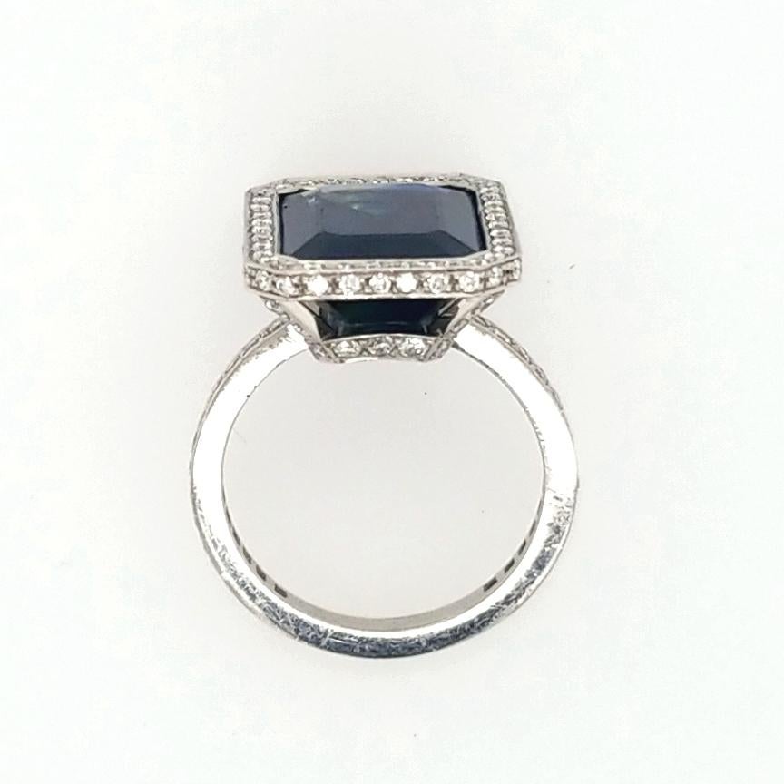 Octagonal Step Cut Transparent Heated Blue Sapphire Center weighing approximately 10.29 carats is bezel set in Platinum. The Ring is GIA certified, certificate number 1206849498, available upon request. Round Brilliant Cut Diamonds weighing 1.76