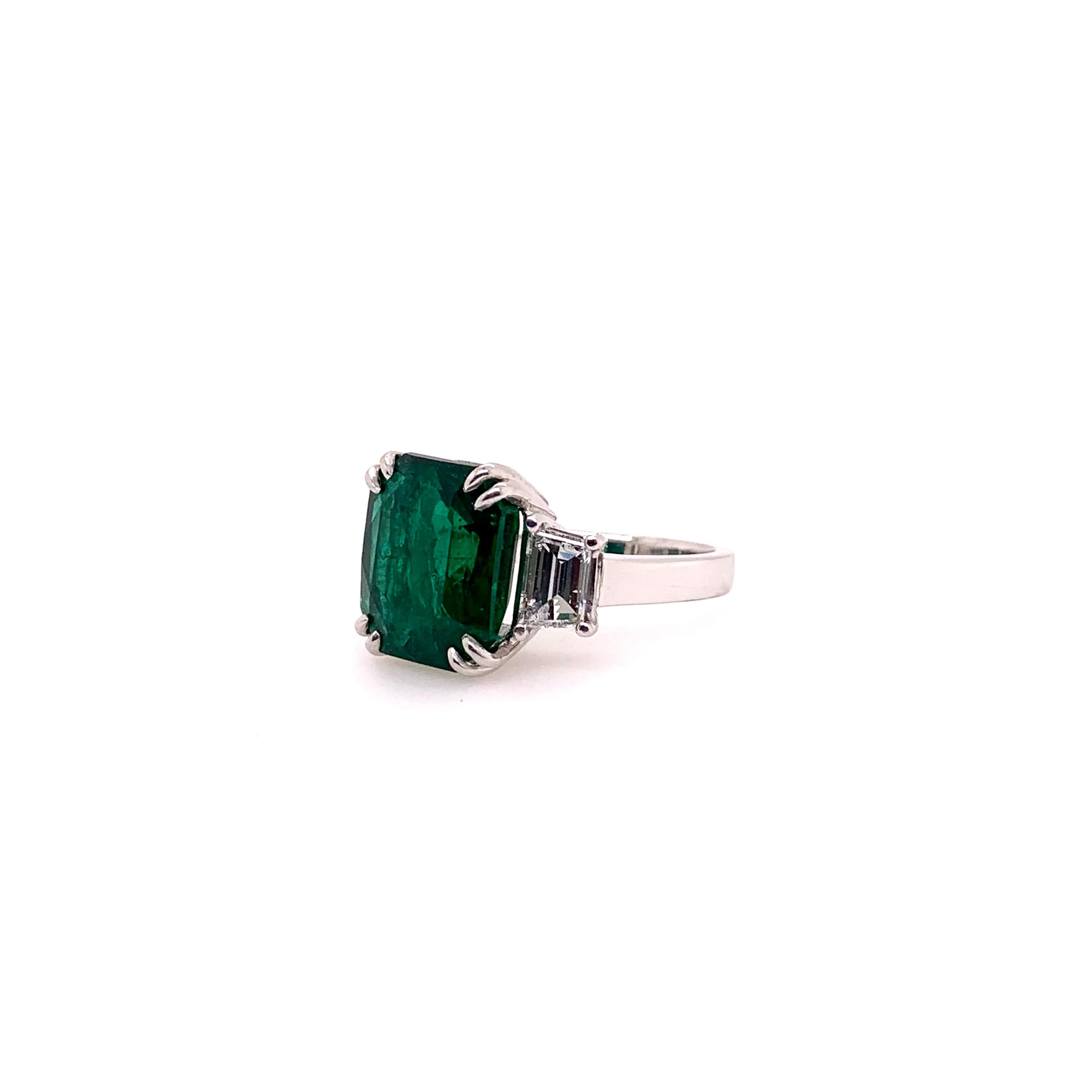 An iconic 3 stone emerald ring with gorgeous trapezoid cut diamonds on the side in a handmade platinum setting!   The 7.68 carat emerald is GIA certified and the trapezoid diamonds weigh 1.20 carats total weight.   This stunning 3 stone ring will be