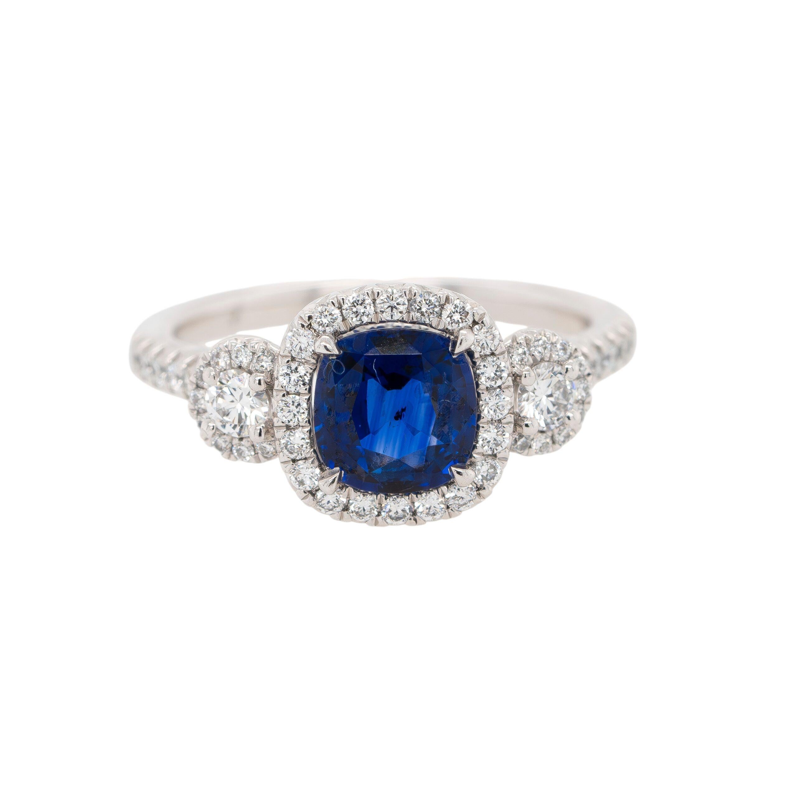 Dieser elegante Halo-Ring aus Platin strahlt zeitlose Raffinesse aus. Im Mittelpunkt steht ein atemberaubender 1,55-karätiger natürlicher Saphir im Kissenschliff, der vom GIA zertifiziert wurde (Report #2223729351). Der Saphir besticht durch seinen