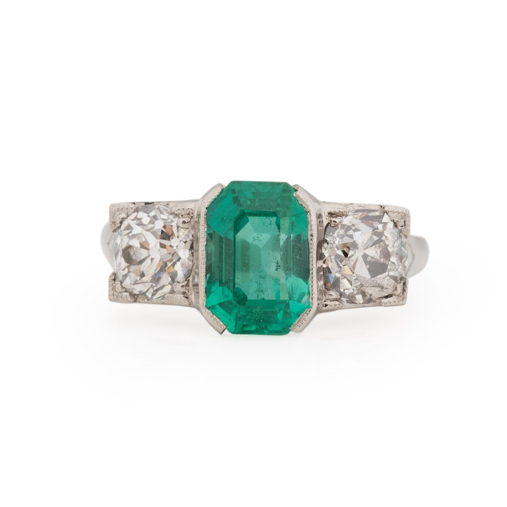 This AMAZING three stone beauty is sure to make heads turn. Crafted in platinum, the classic shank design it the perfect match for what it holds. In the center we have a breathtaking F1 natural Zambian emerald, this emerald has minimal treatment and