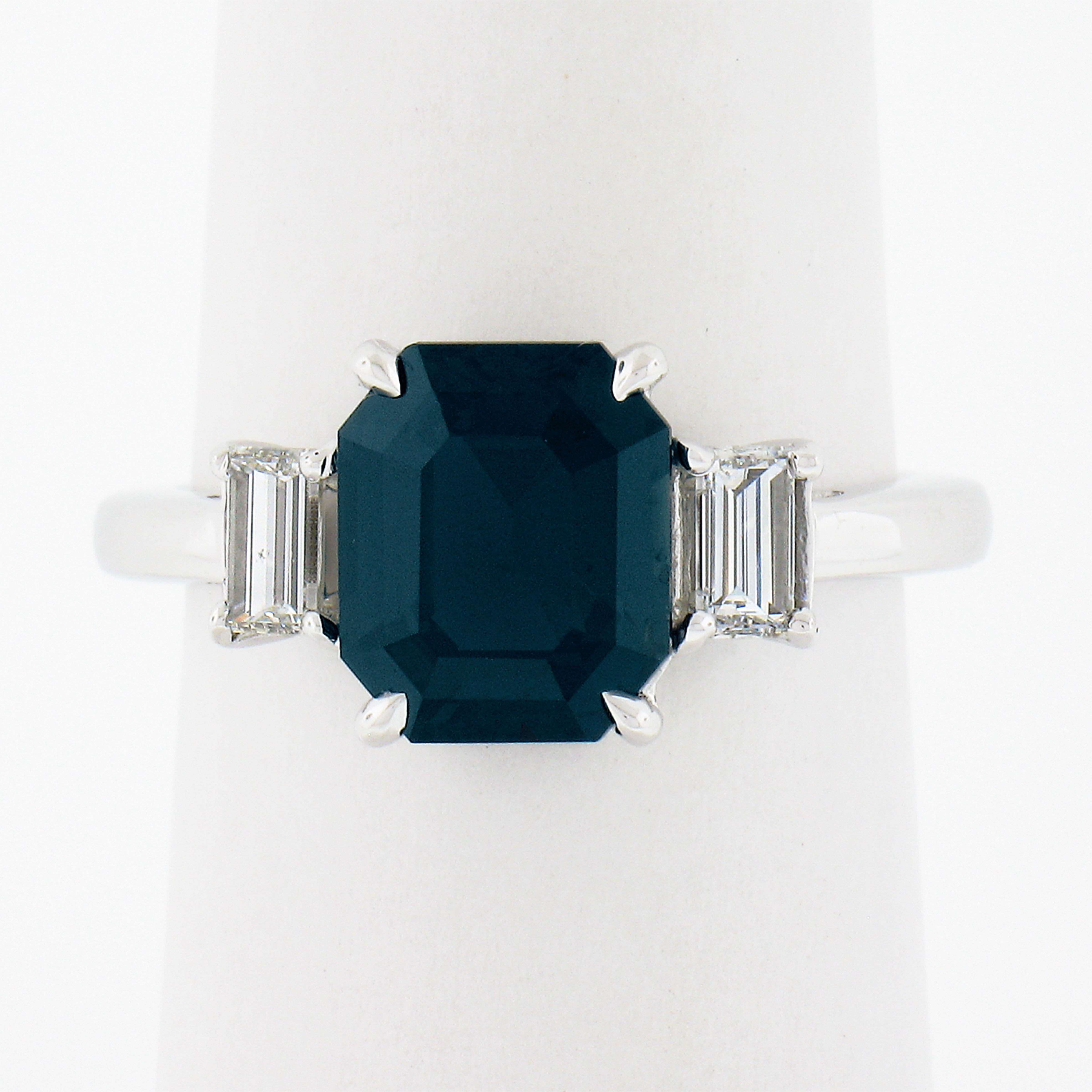 This classy and elegant sapphire engagement or three stone ring is crafted in solid platinum and features a GIA certified, 3.03 carat unique greenish blue sapphire solitaire, neatly prong set in the center and flanked on either side with a fine