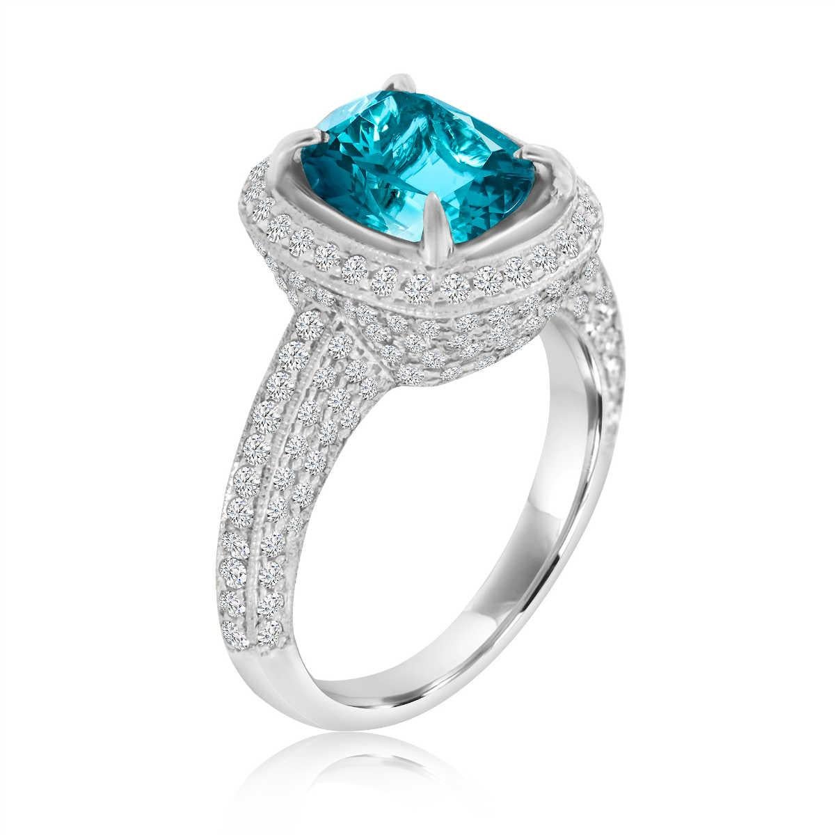 This Pre-Owned Red Carpet stunning Platinum ring features a 4.38-carat cushion-shaped vibrant Blue Zircon encircled by a halo of brilliant round diamonds. A pave' set of dazzling diamonds covering the vintage-designed crown and along the ring's