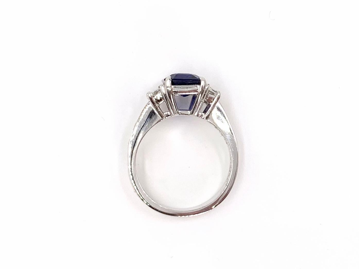 A classic and elegantly designed platinum ring by JB Star featuring a vivid, well saturated 3.22 emerald cut royal blue sapphire beautifully flanked by step-cut trapezoids and baguettes. Sapphire is of a very fine color and make with medium