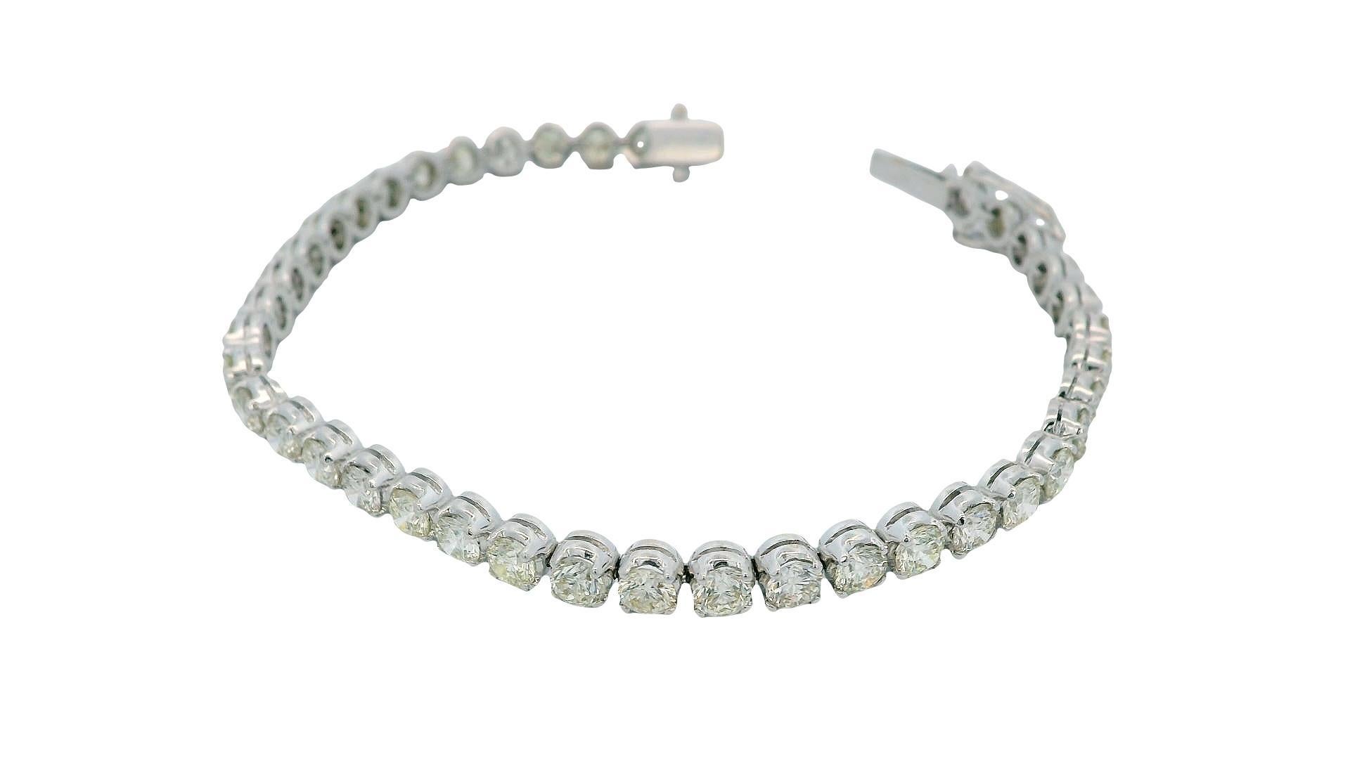 Esta impresionante pulsera, del siglo XXI, muestra un elegante diseño compuesto por una cadena continua de diamantes talla redonda. El peso total de los diamantes es de aproximadamente 6,8 quilates, y exhiben un tono blanco brillante, clasificados