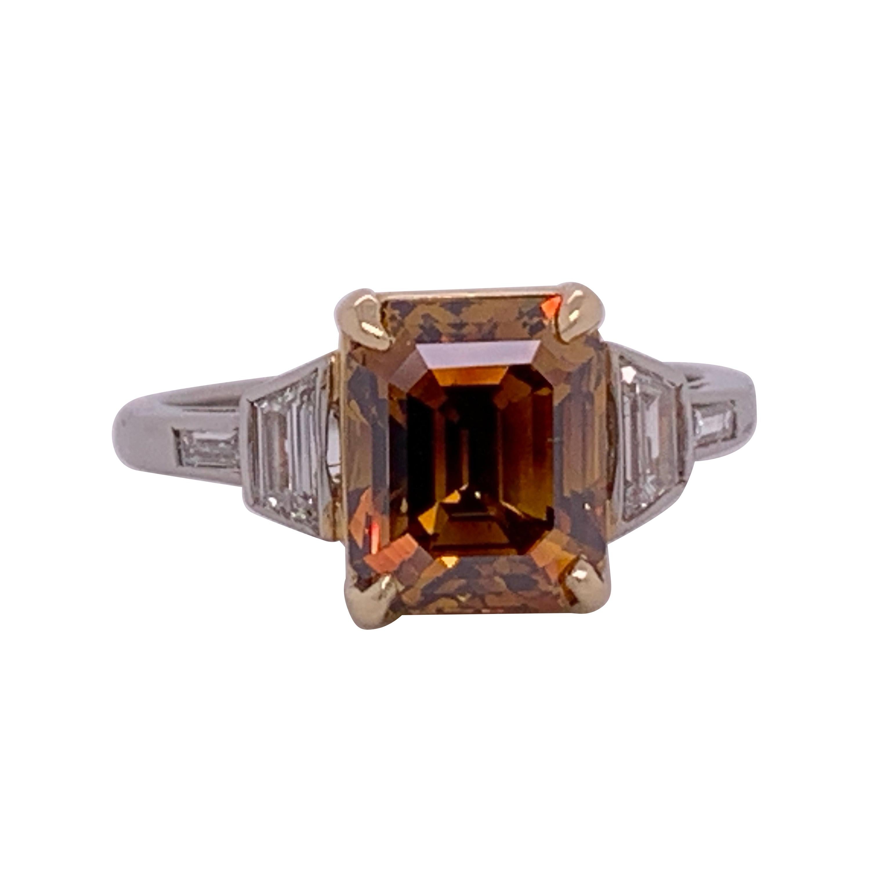 A rare Deep Orange-Brown Emerald Cut weighing 3.37 carat and certified by the GIA as an SI1 in clarity. Pleasant rectangular shape and extraordinary color. Ring is a size 6.25. The platinum ring contains approximately 0.35cts. 