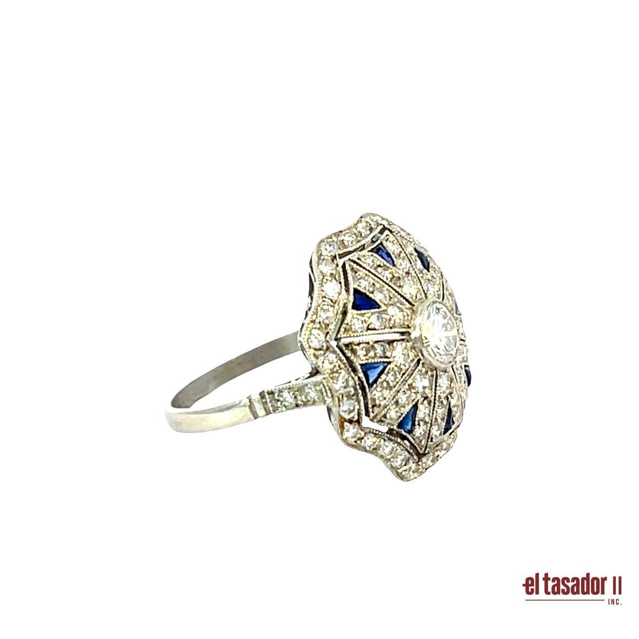Questo squisito anello in platino è una creazione artigianale con un audace design ottagonale e pesa 5,3 grammi. Al centro si trova un diamante taglio brillante di 0,40 carati, circondato da 0,33 carati di zaffiri taglio calibro blu profondo