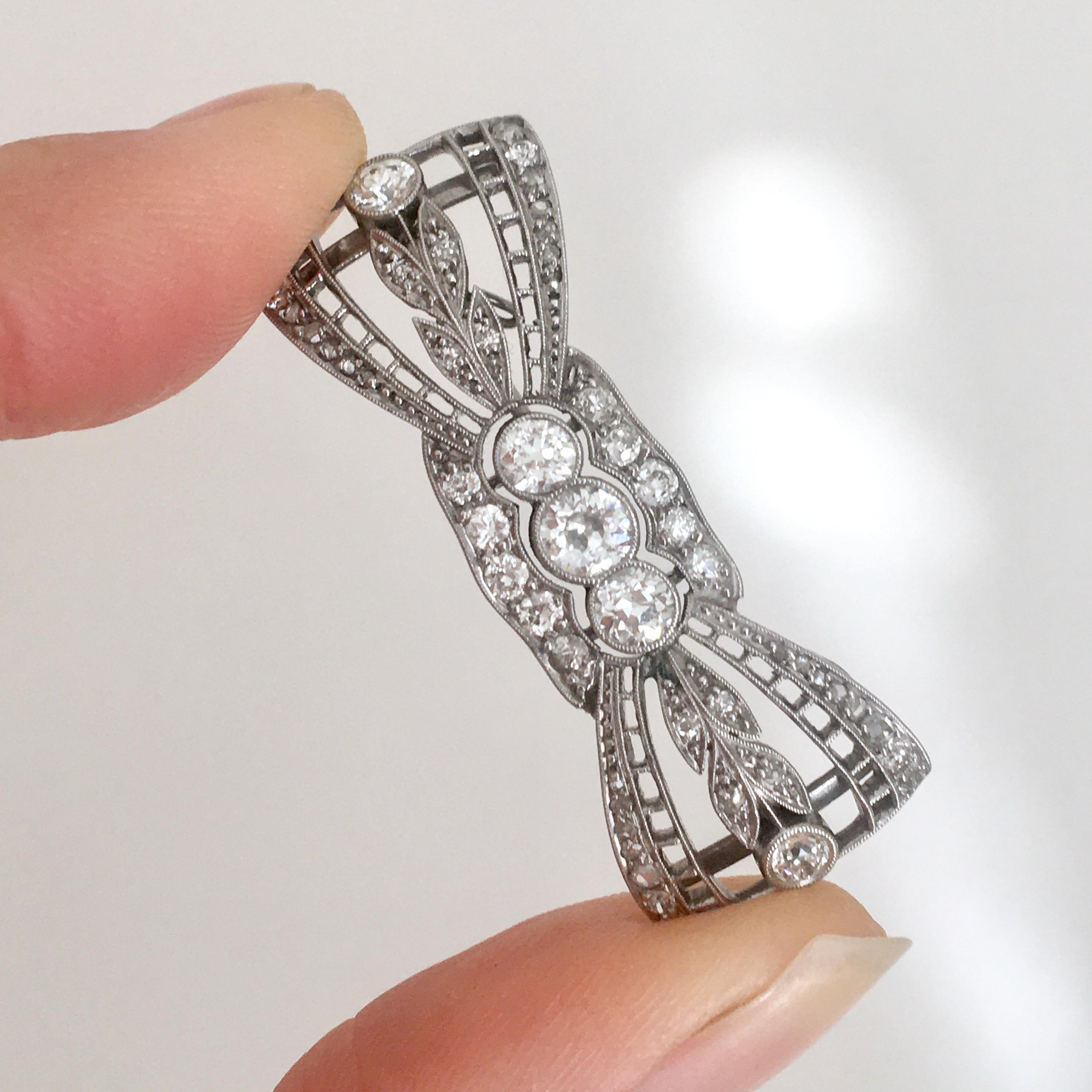 A magnificent Art Deco bow brooch made of platinum and many diamonds. The brooch dates from the 1930s and has a beautiful openwork and leave design which is set with old cut diamonds. The diamonds displaying a fine white color, brilliance and
